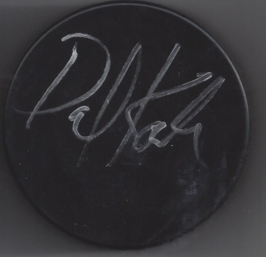 A black hockey puck with a white signature on it.