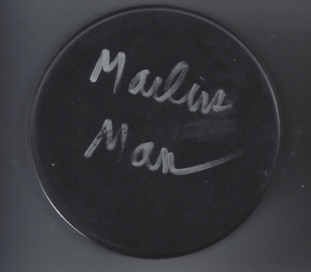 Close-up of a black circular object with the handwritten words 'Malvin Man' in white.