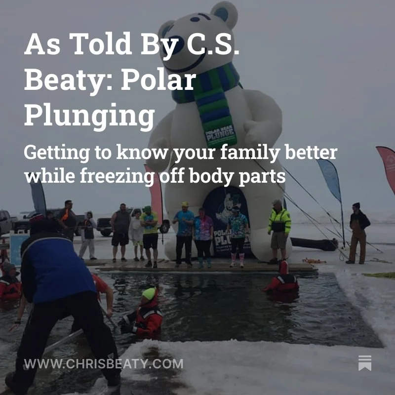 A polar bear-shaped inflatable structure with people gathering around and participating in a polar plunge event in icy water, with a snow-covered background.