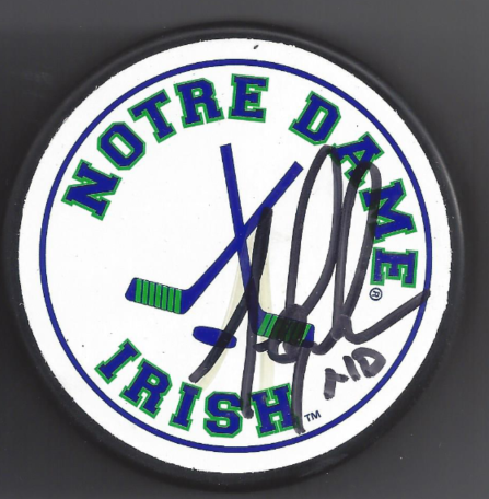 A clock-shaped sign with Notre Dame Irish logo and signature, featuring a clock face with green and blue elements.