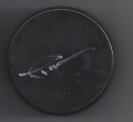 A black hockey puck with a signature on it.
