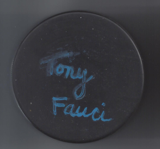 Black circular object with blue handwriting that says 'Tory Fauci'.