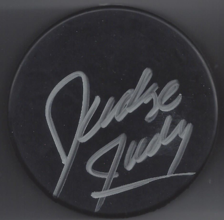 Black hockey puck with white signature.