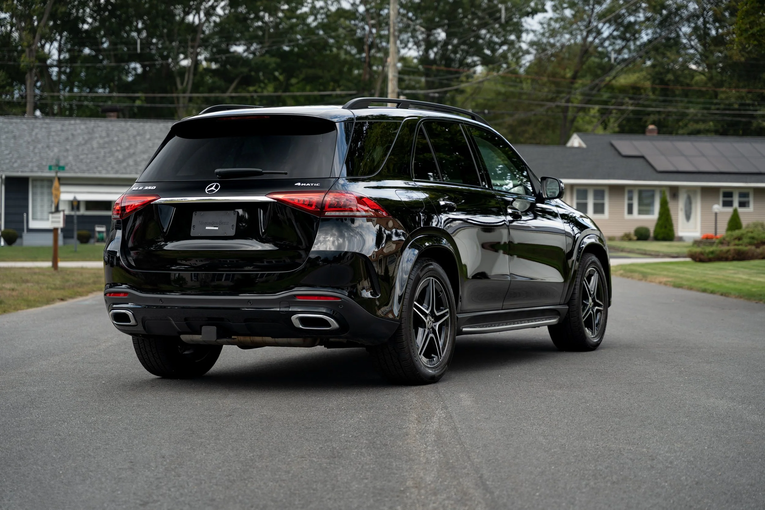 Black Mercedes-Benz SUV parked on a residential street with houses and trees in the background.