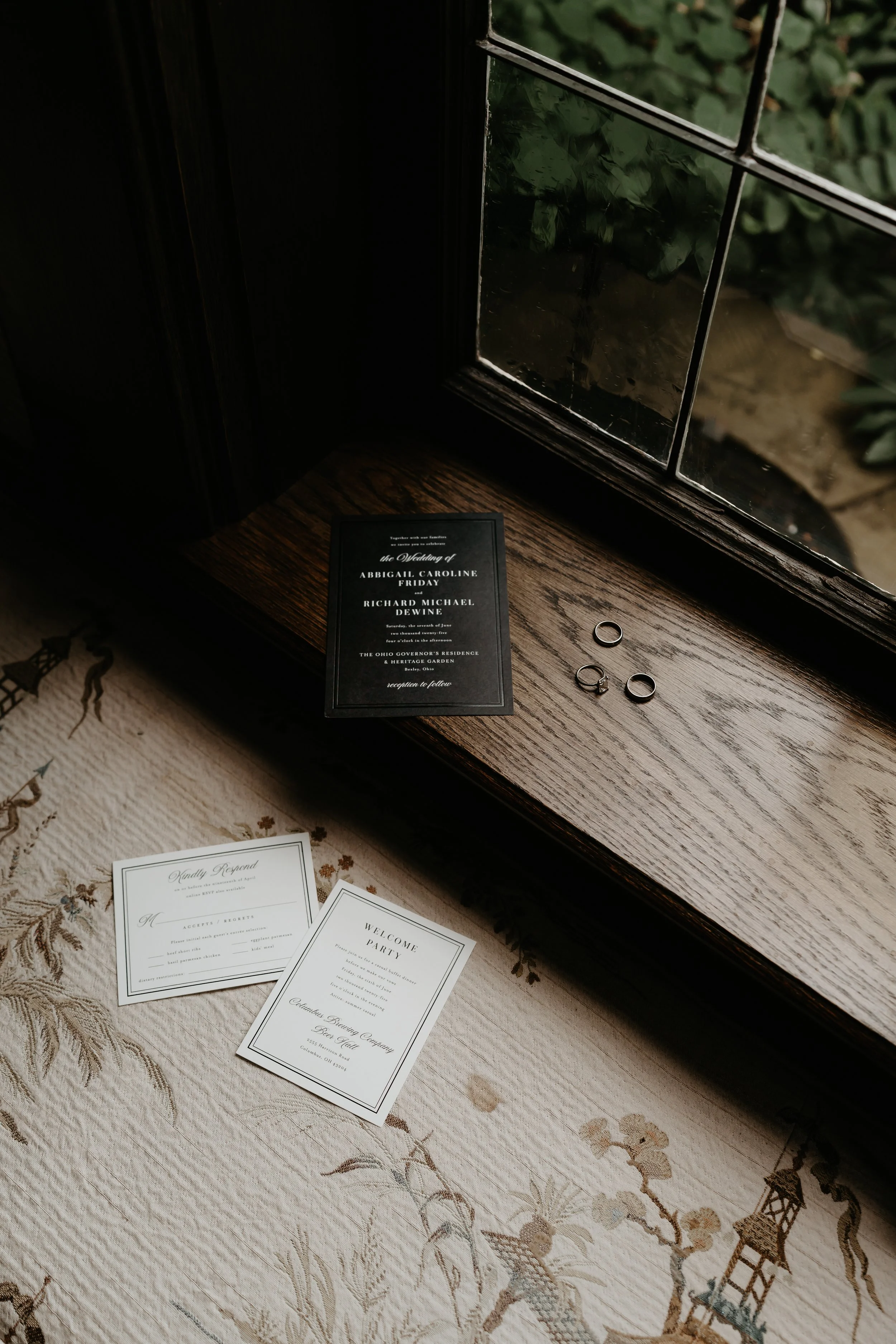 Black-and-white wedding stationery and rings arranged beside a historic window inside the Ohio Governor’s Residence, photographed by Julia Brown Photo.
