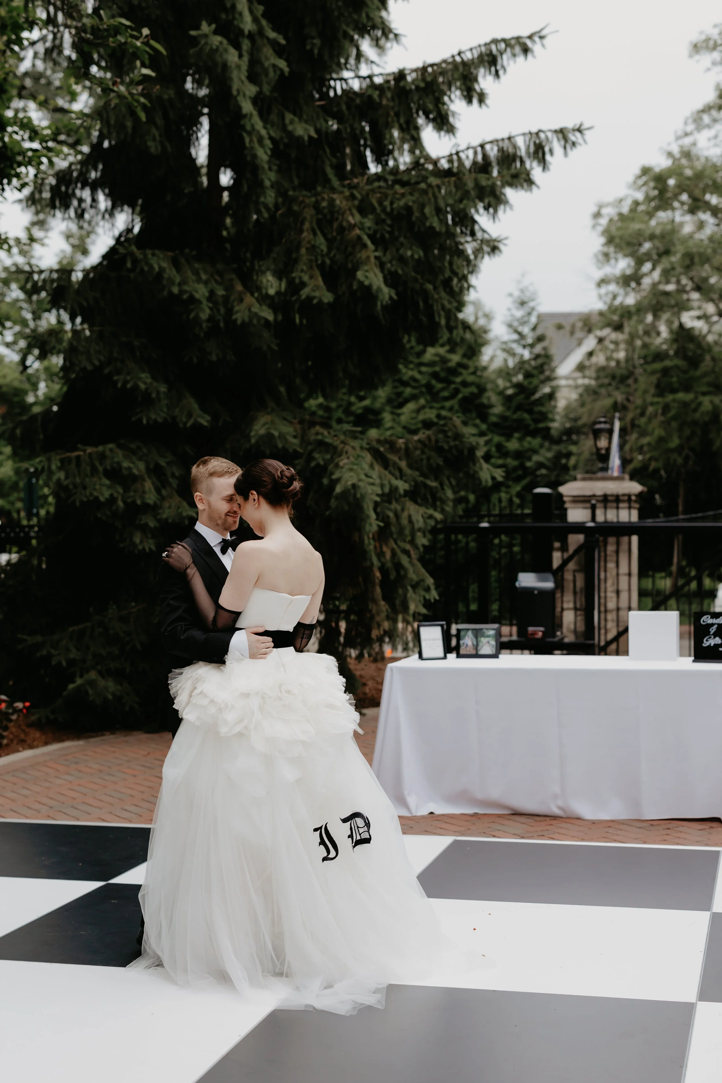 Bride and groom first dance on a black-and-white checkered outdoor dance floor dance floor during their Bexley, Ohio wedding celebration, photographed by Julia Brown Photo.