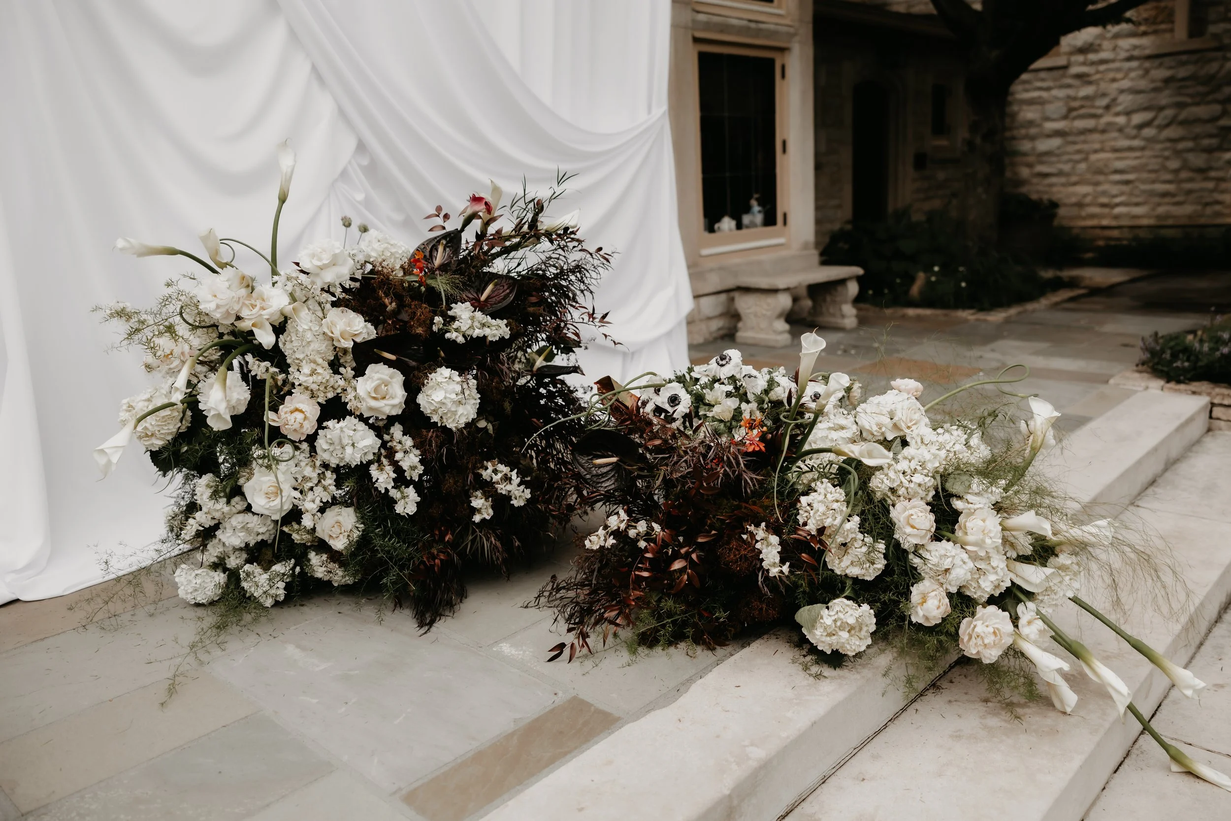 Organic white and dark-toned wedding florals arranged along the ceremony steps at the Ohio Governor’s Residence, photographed by Julia Brown Photo.