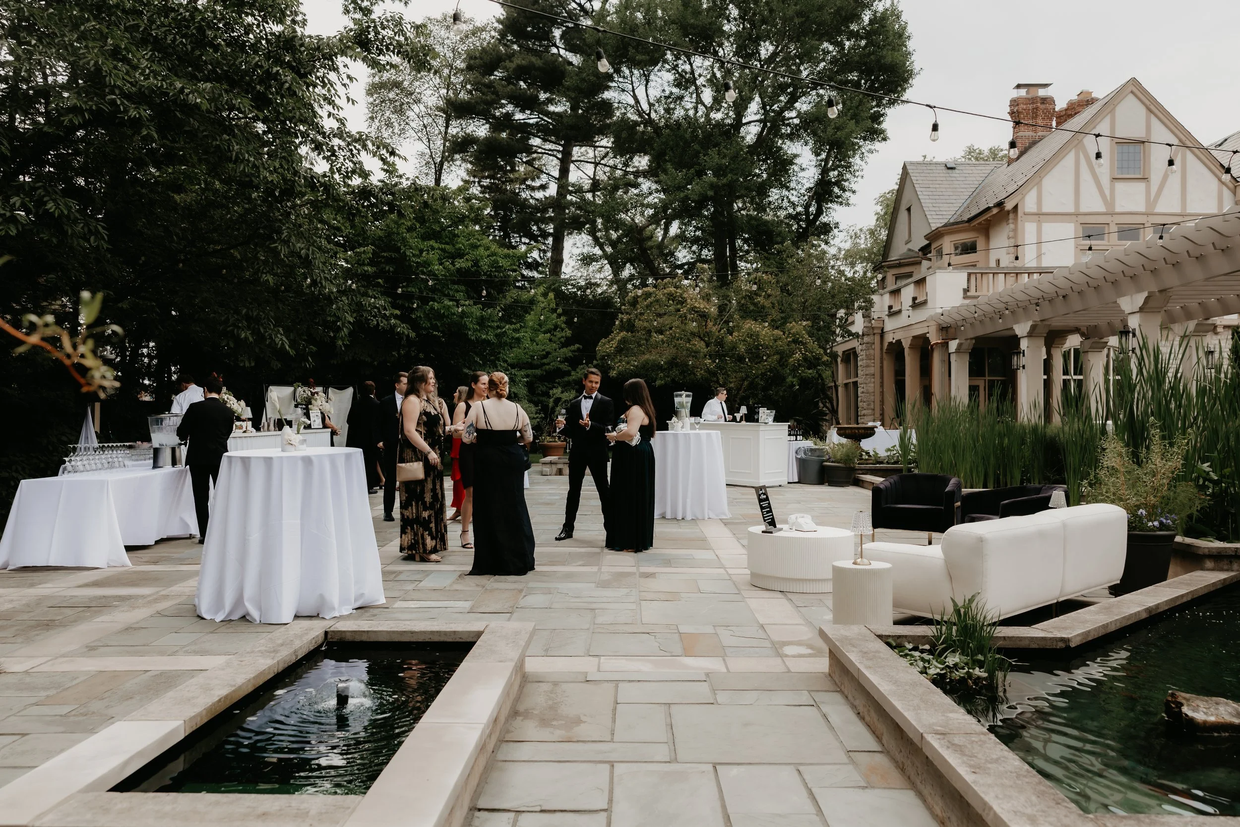 Wedding guests gathering for cocktail hour beside the reflecting pools and gardens at the Ohio Governor’s Residence, photographed by Julia Brown Photo.