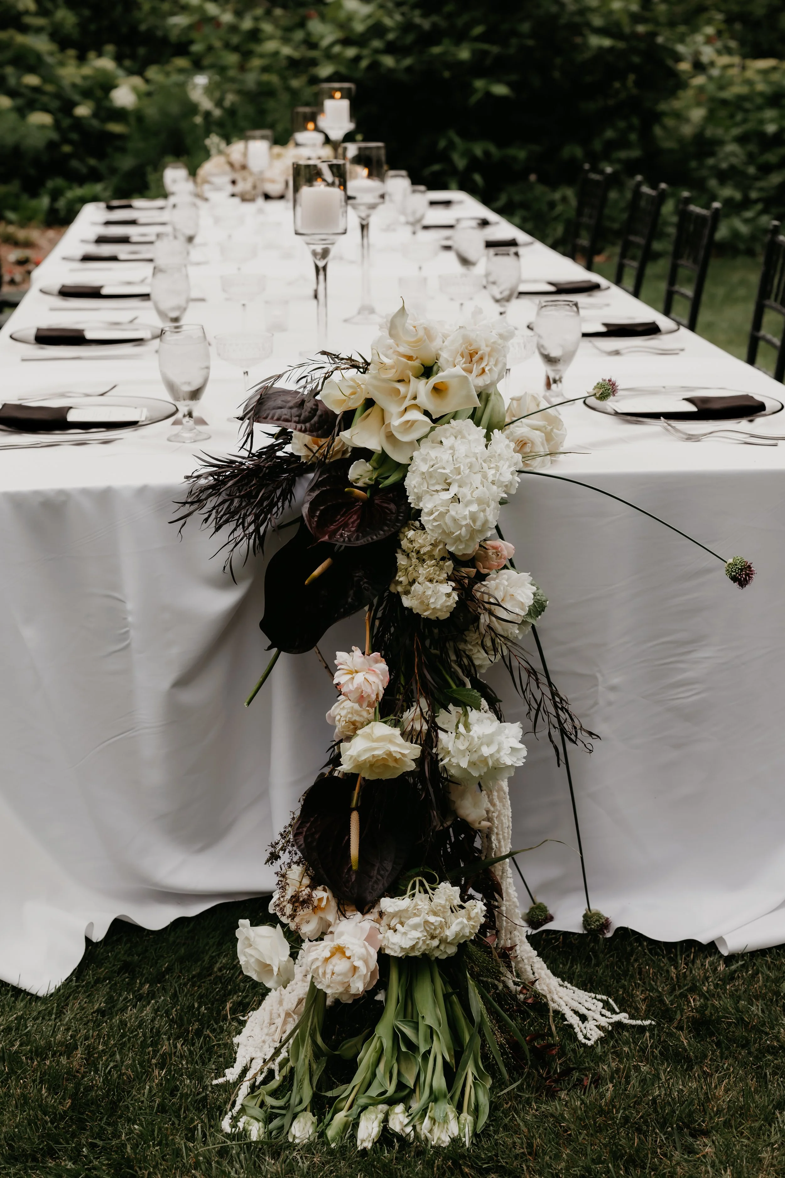 White wedding reception table accented with organic floral arrangements and modern black place settings, photographed by Julia Brown Photo.