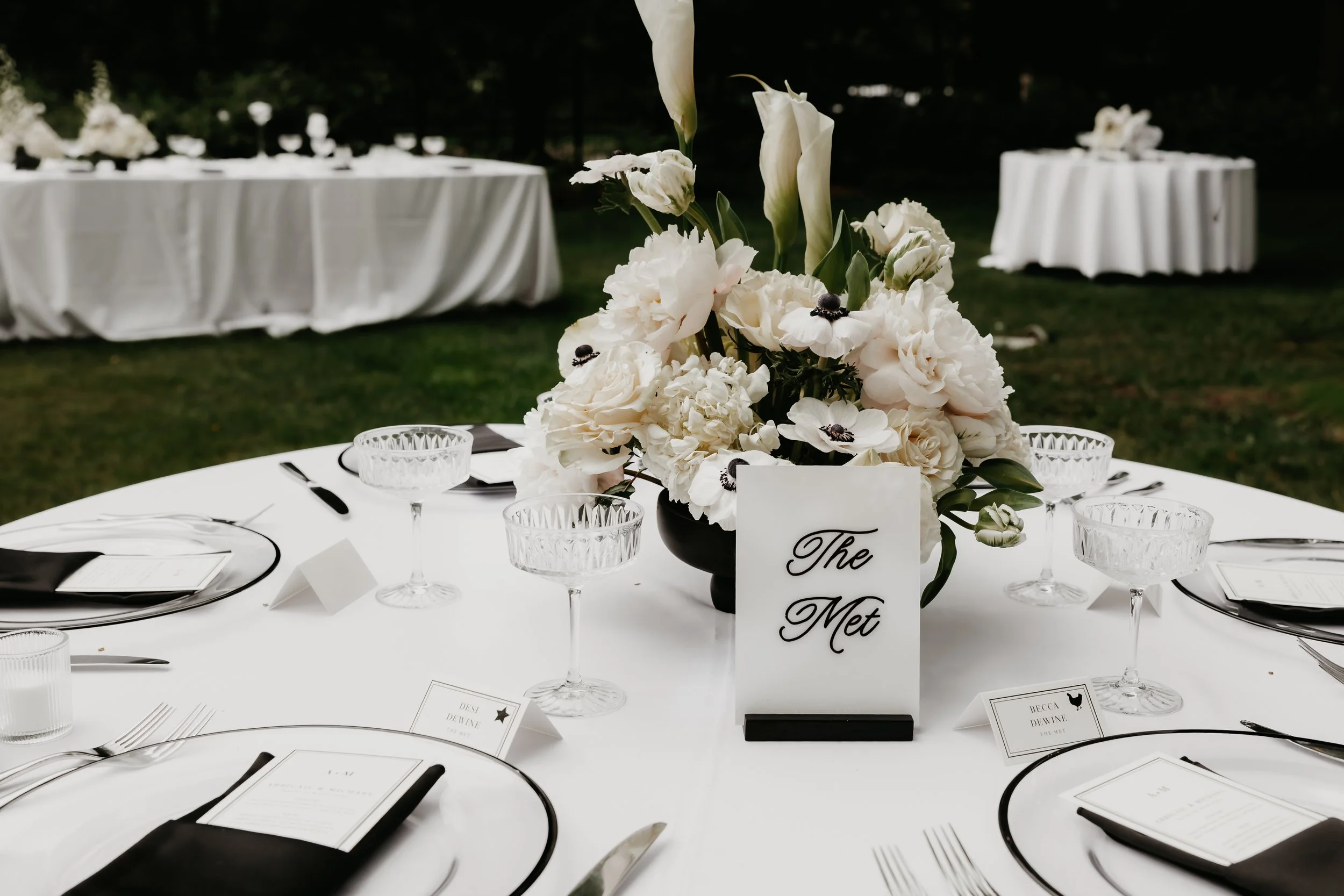New York City-inspired wedding table setting with white florals and a table sign reading The Met, photographed by Julia Brown Photo.