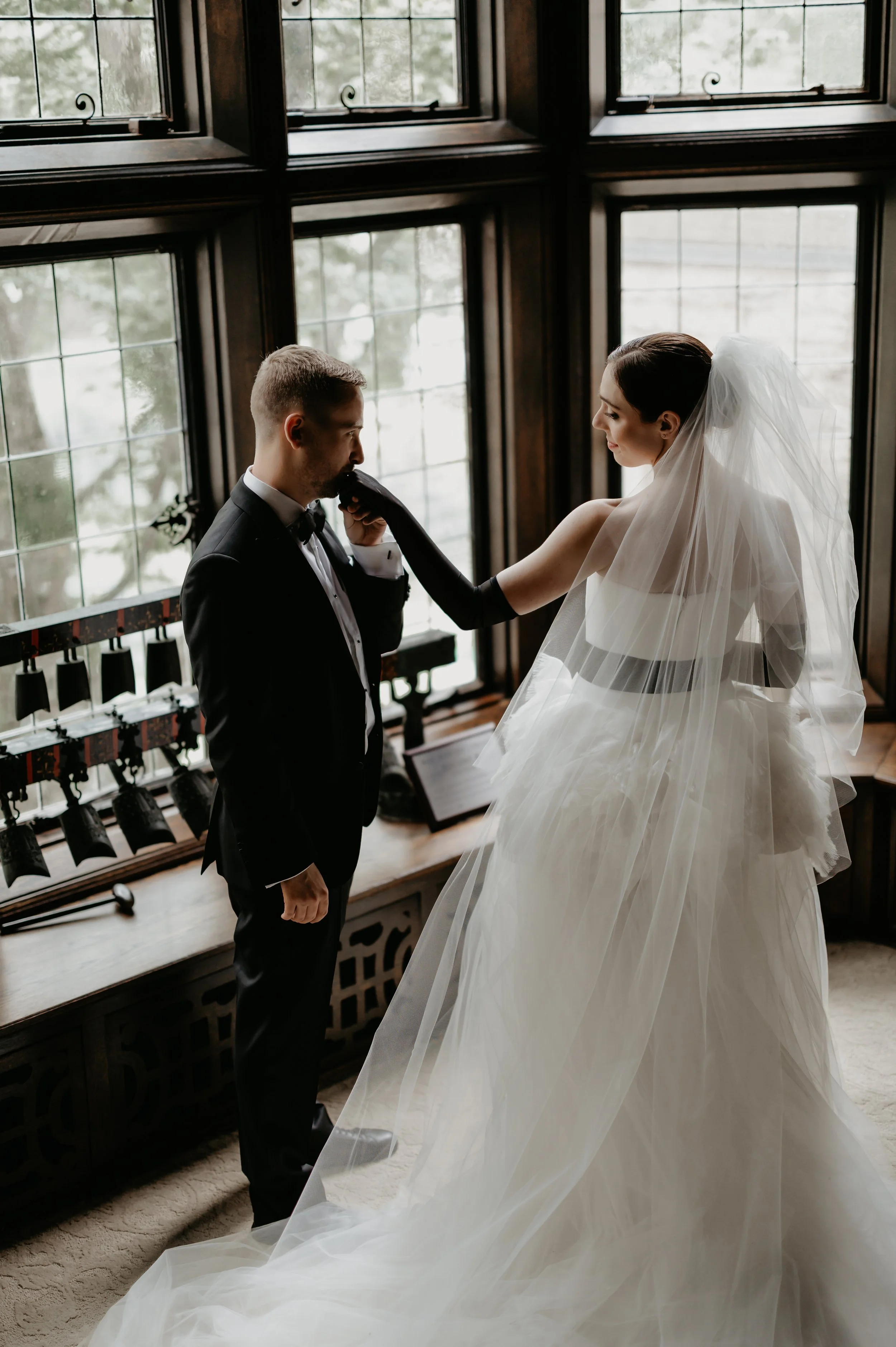 Bride adjusting the groom’s boutonniere beside historic windows inside the Ohio Governor’s Residence, photographed by Julia Brown Photo.