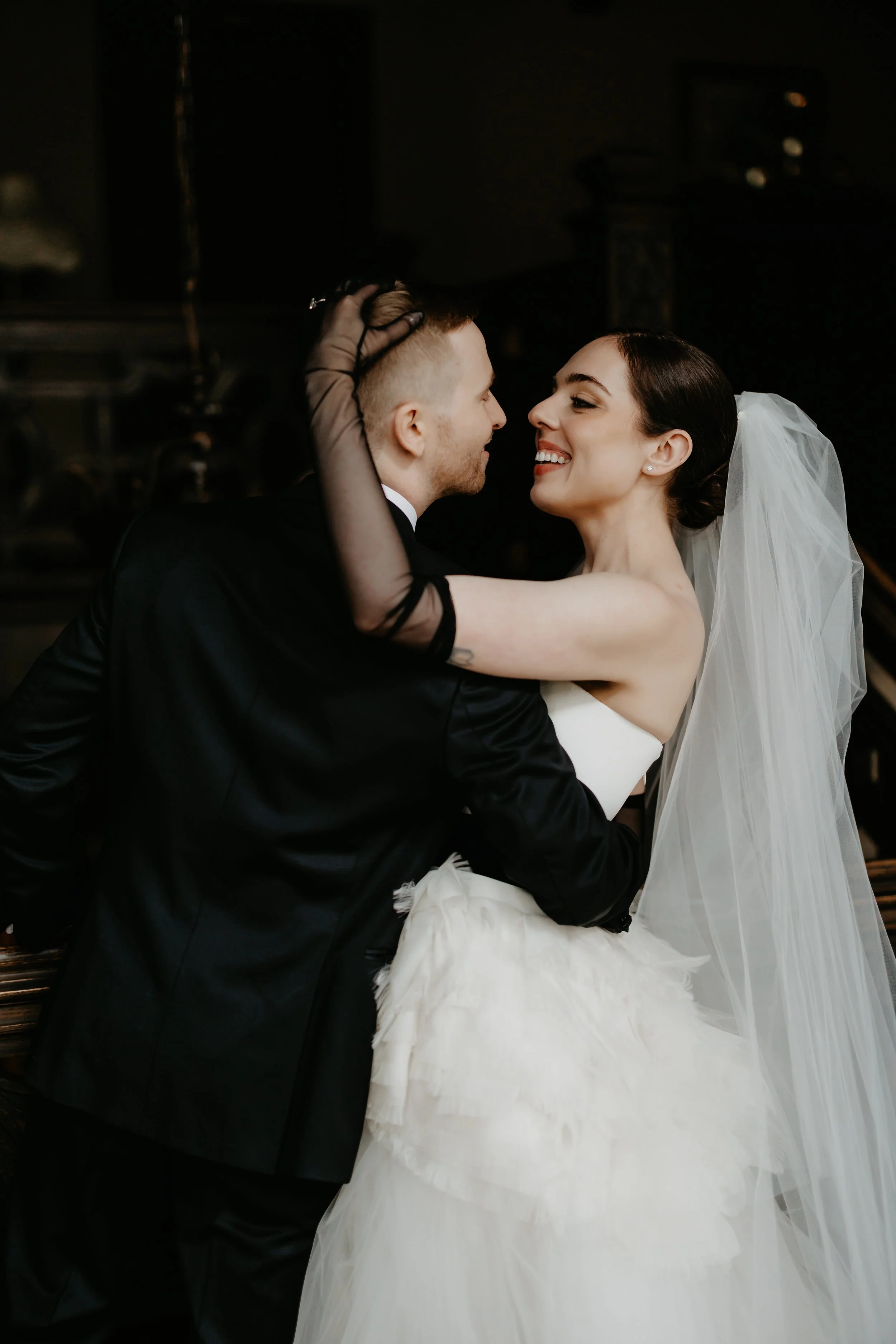 Bride and groom smiling at one another with dark background during an intimate wedding portrait inside the Ohio Governor’s Residence, photographed by Julia Brown Photo.