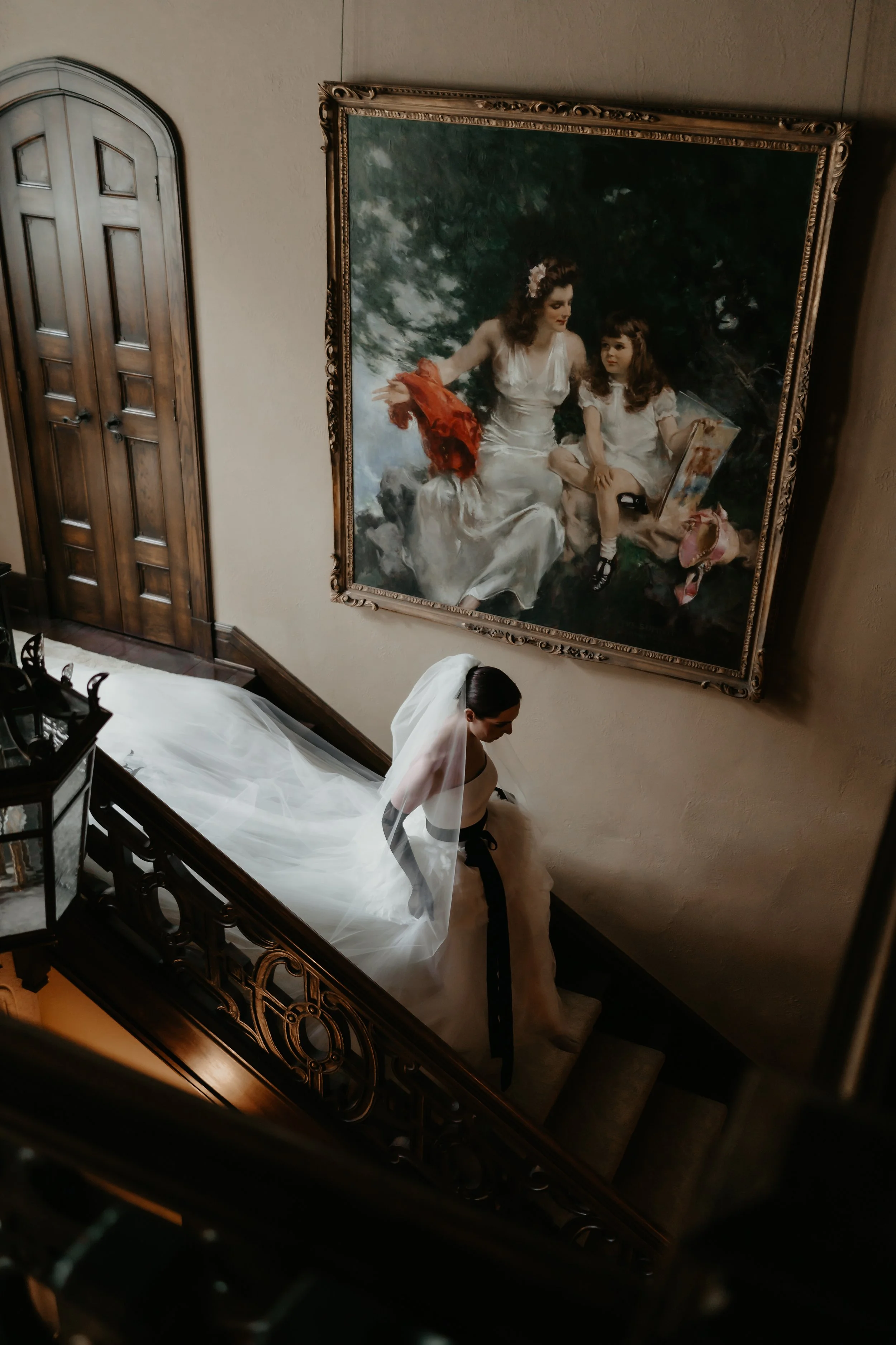 Bride descending the historic staircase beneath a large portrait inside the Ohio Governor’s Residence, photographed by Julia Brown Photo.