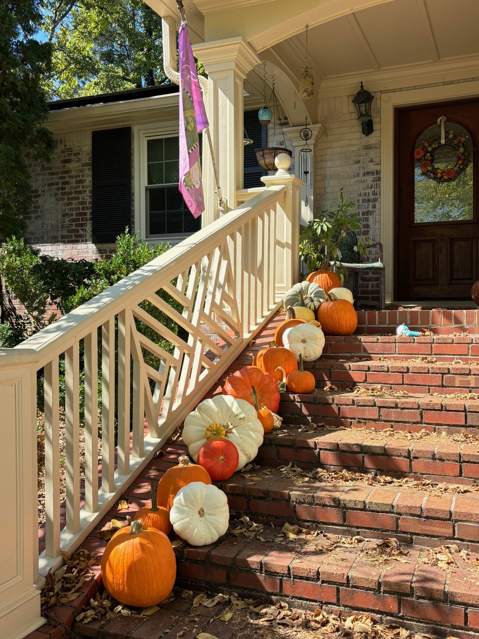 Front porch decorated with a variety of pumpkins and gourds in orange, white, green, and cream colors