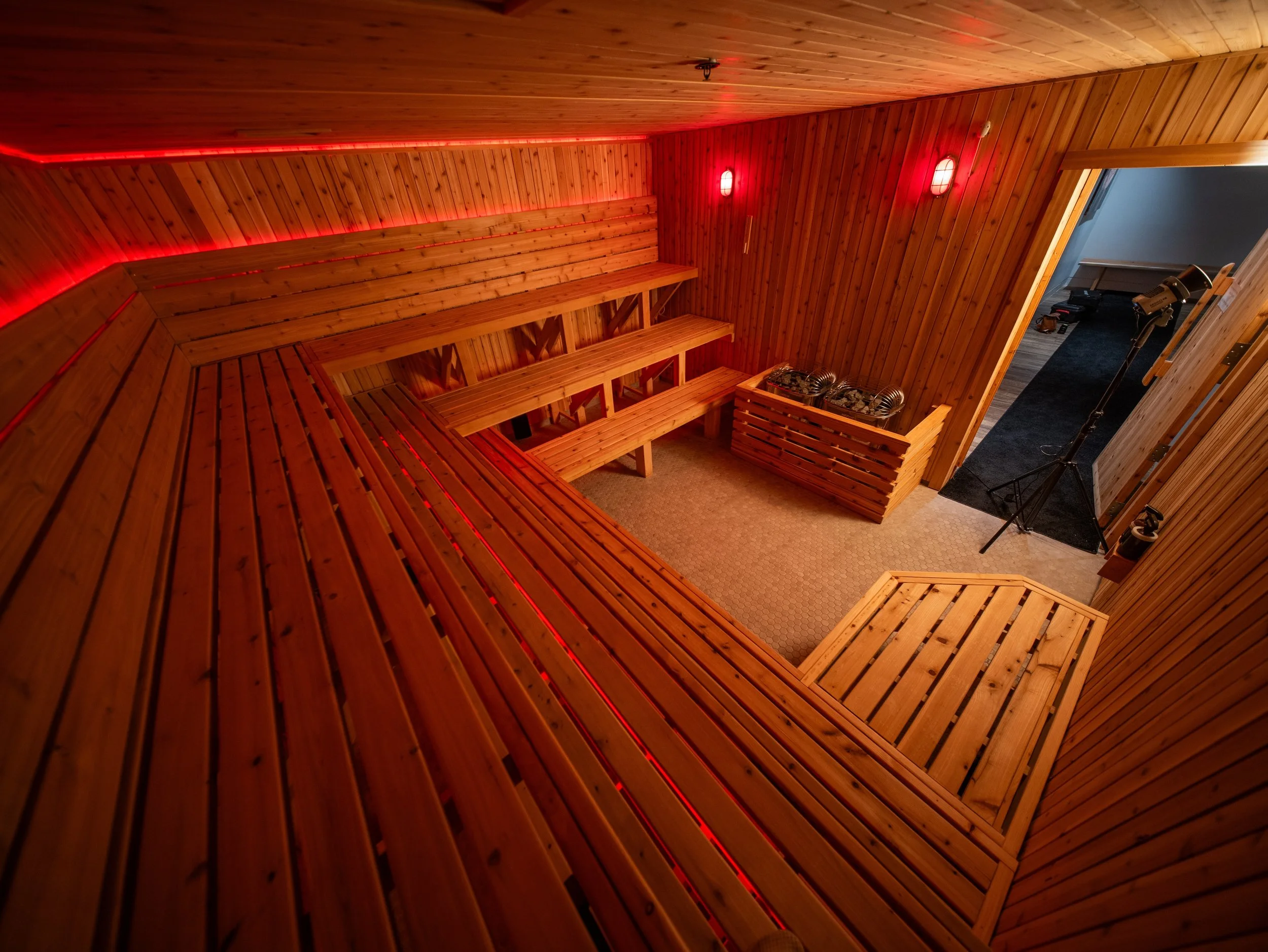 Interior of a custom-built sauna by Hot Bird Saunas with tiered cedar seating and integrated red LED lighting.