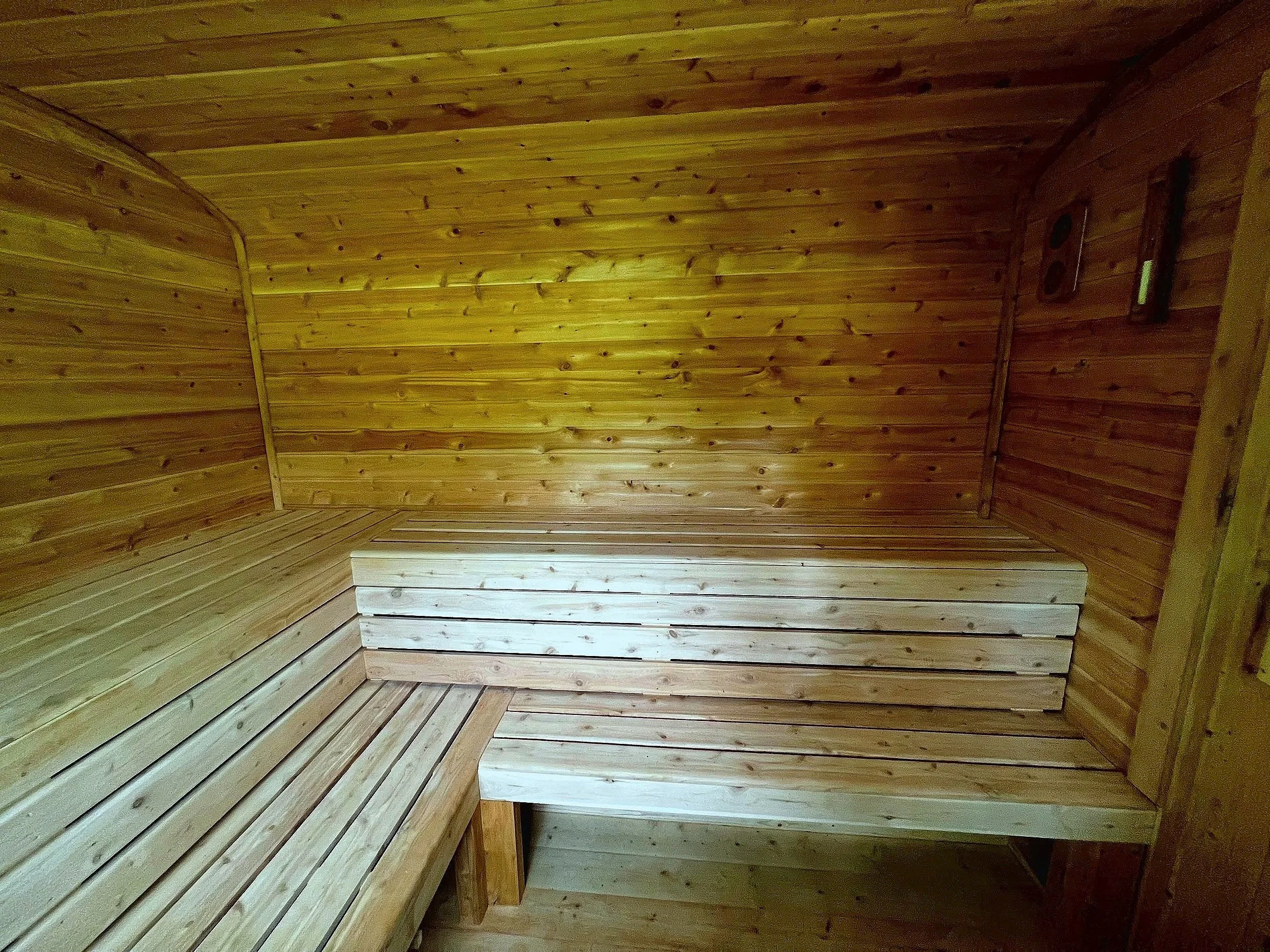Interior of a custom-built sauna by Hot Bird Saunas with bench seating along two walls and smooth, clear cedar.