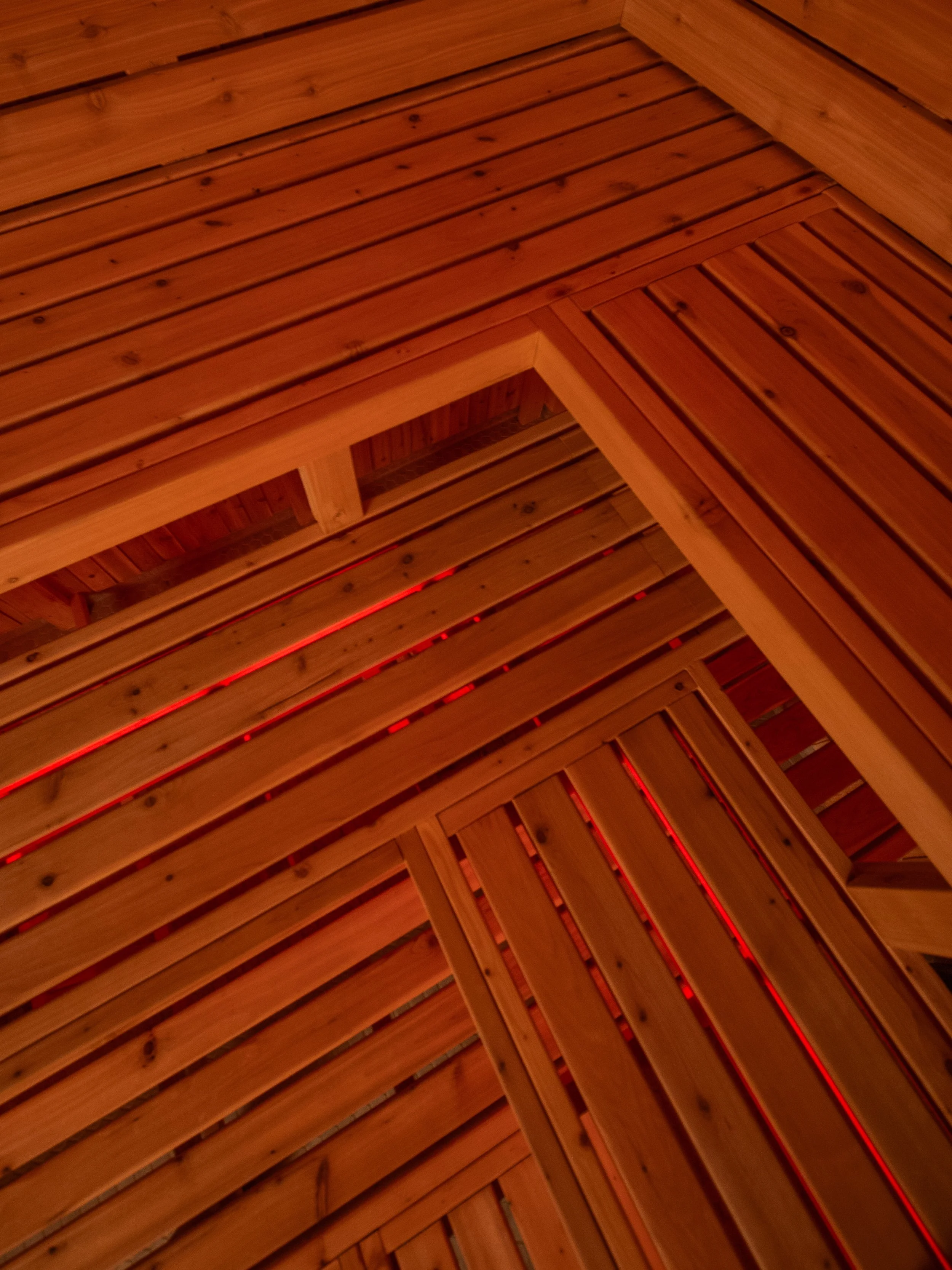 Sauna bench detail inside a custom-built sauna by Hot Bird Saunas, highlighting clear cedar and integrated red LED lighting.