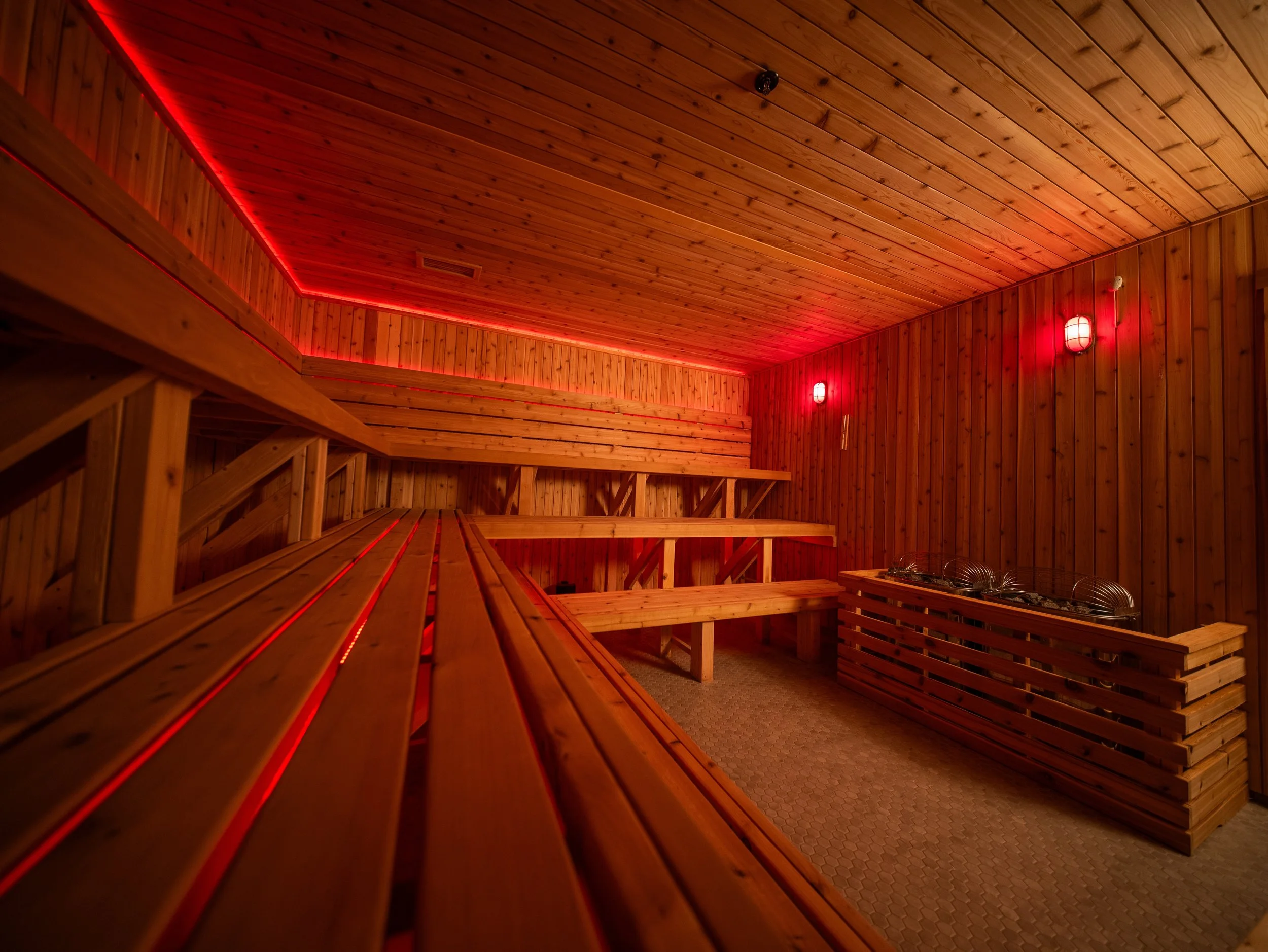 Interior of a custom-built sauna by Hot Bird Saunas, featuring cedar benches, cedar tongue and groove walls and ceiling, and integrated red LED lighting.