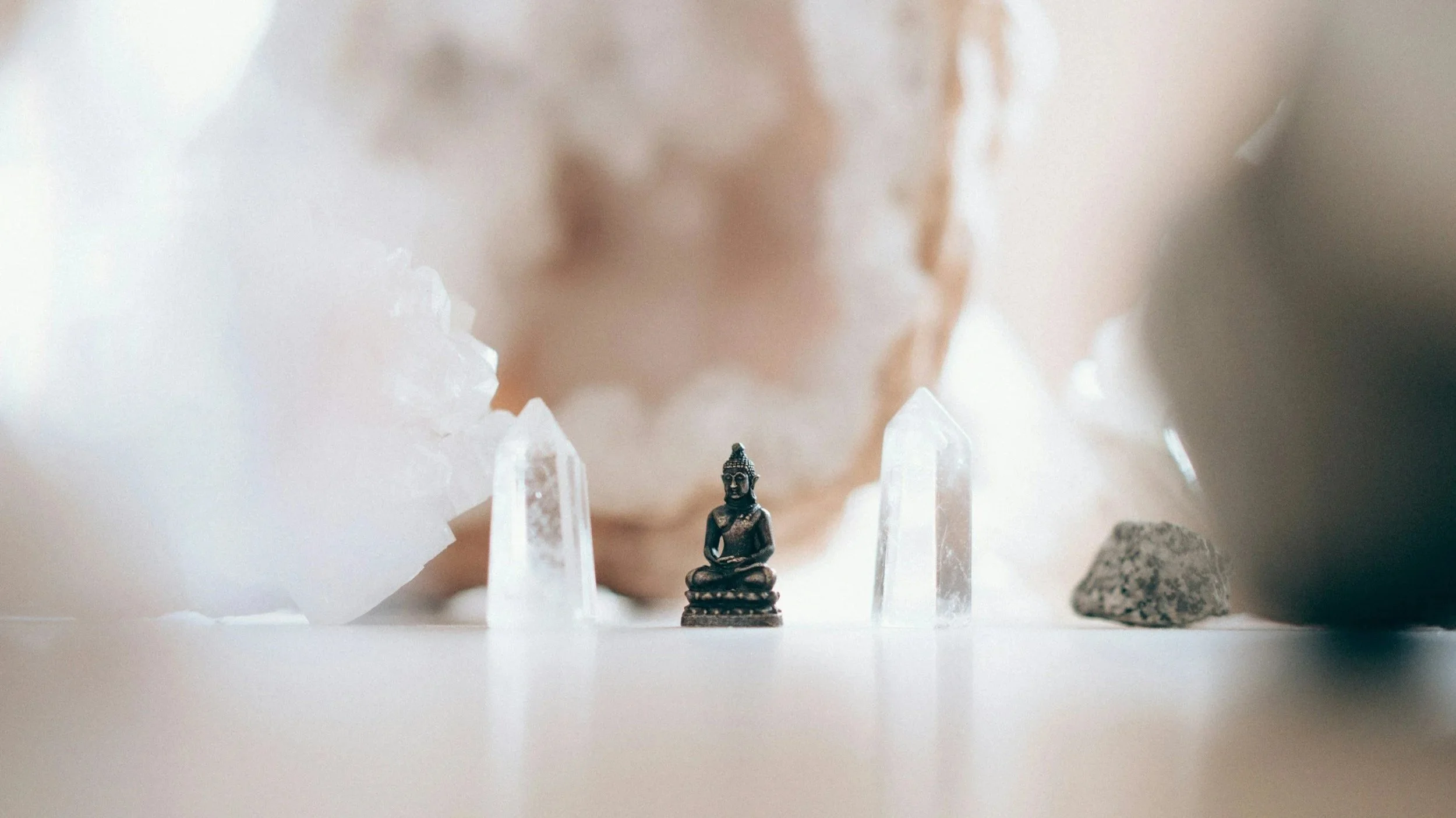 Small Buddha statue with crystals on a softly blurred background.
