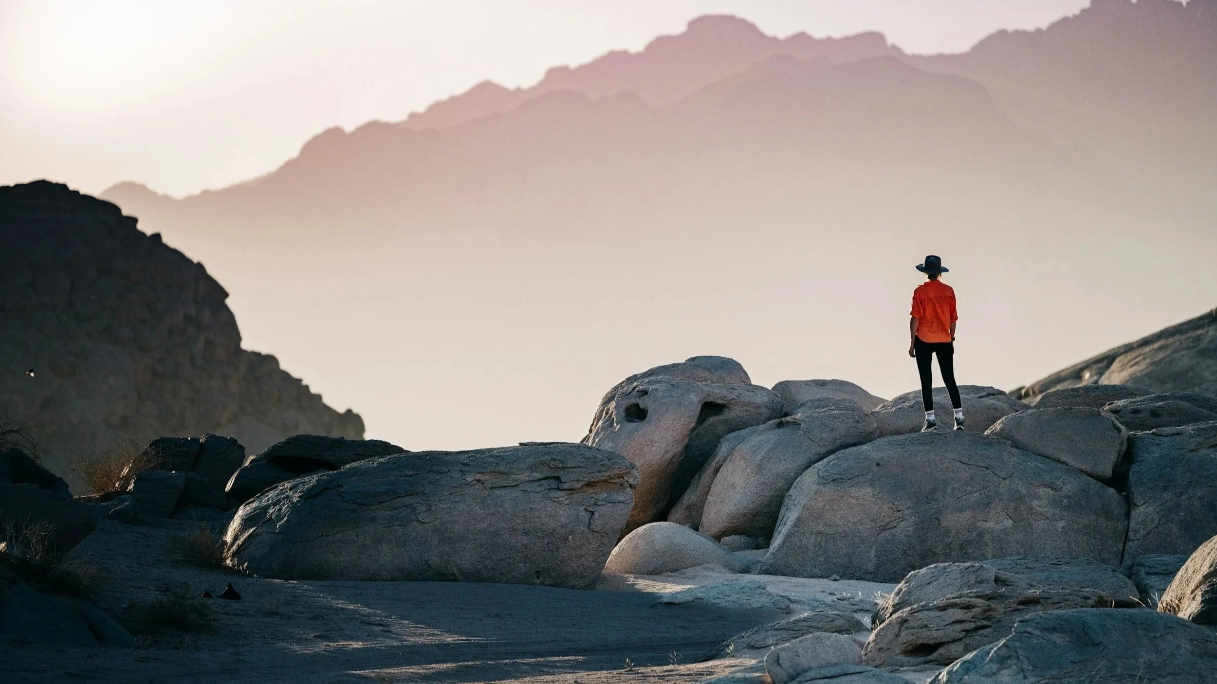 Person standing on rocks looking out towards the horizon.