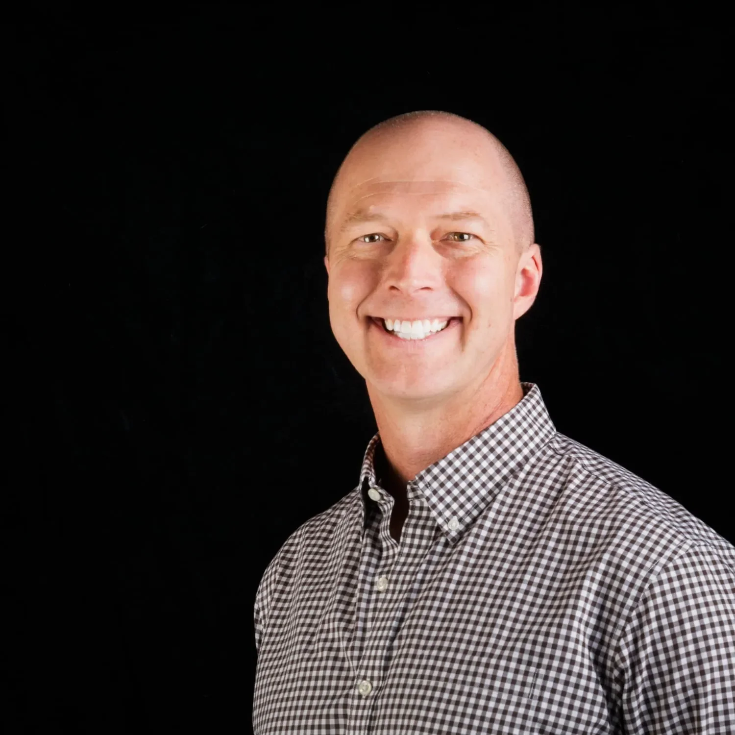 Professional photographer Michael Kloth, MFA, CPP smiling in front of a black background.