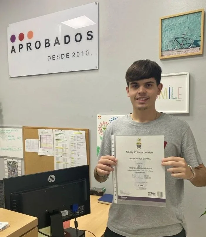 Joven sonriendo sosteniendo un certificado en una oficina