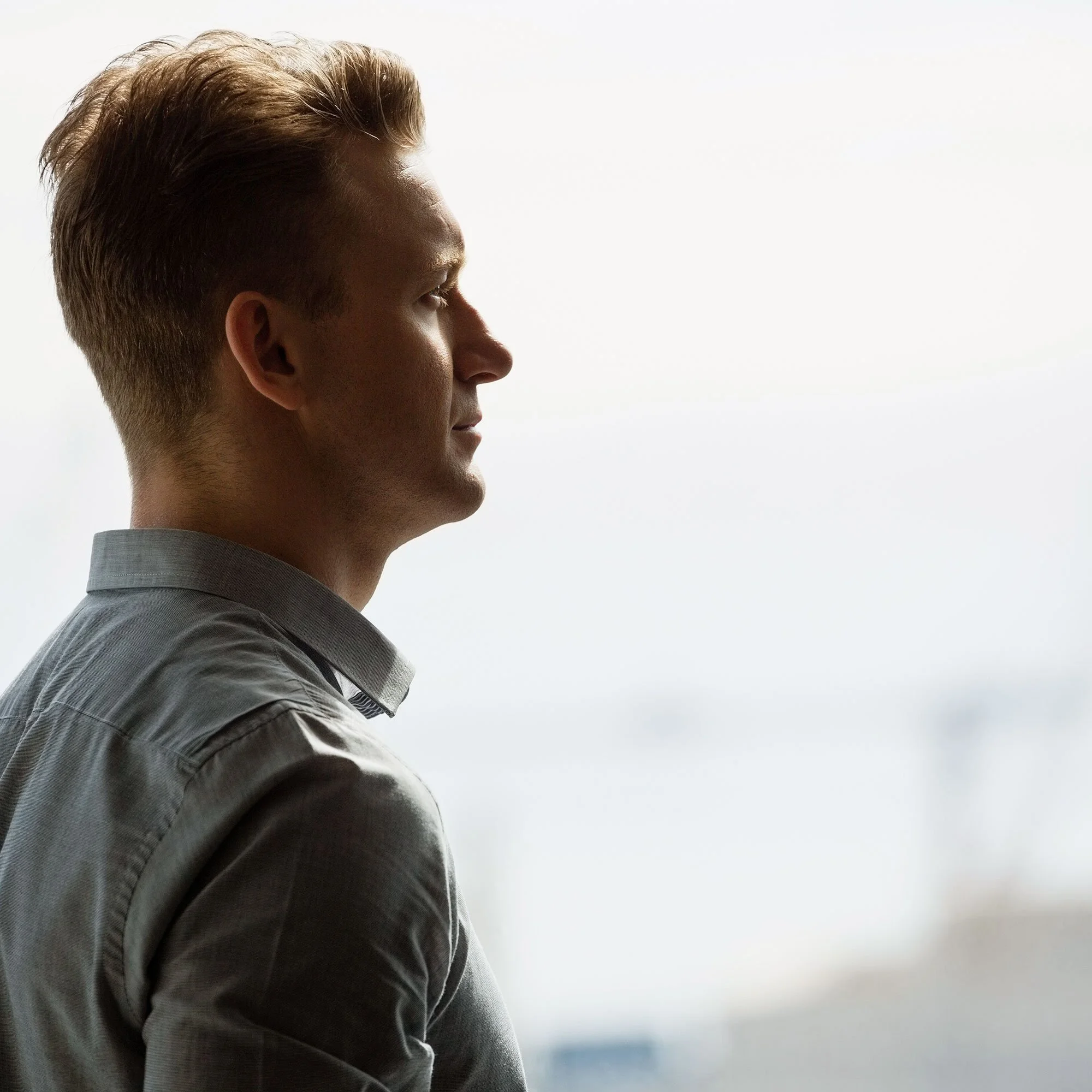 Side profile of a man with light brown hair looking out a window.