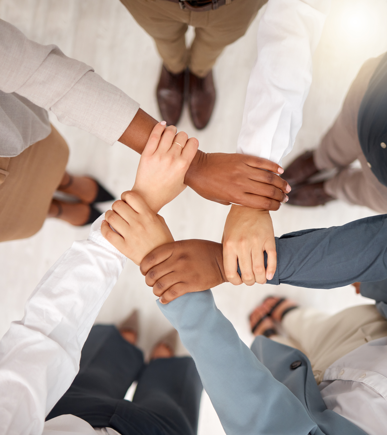 Group of diverse people placing their hands together in a gesture of teamwork.