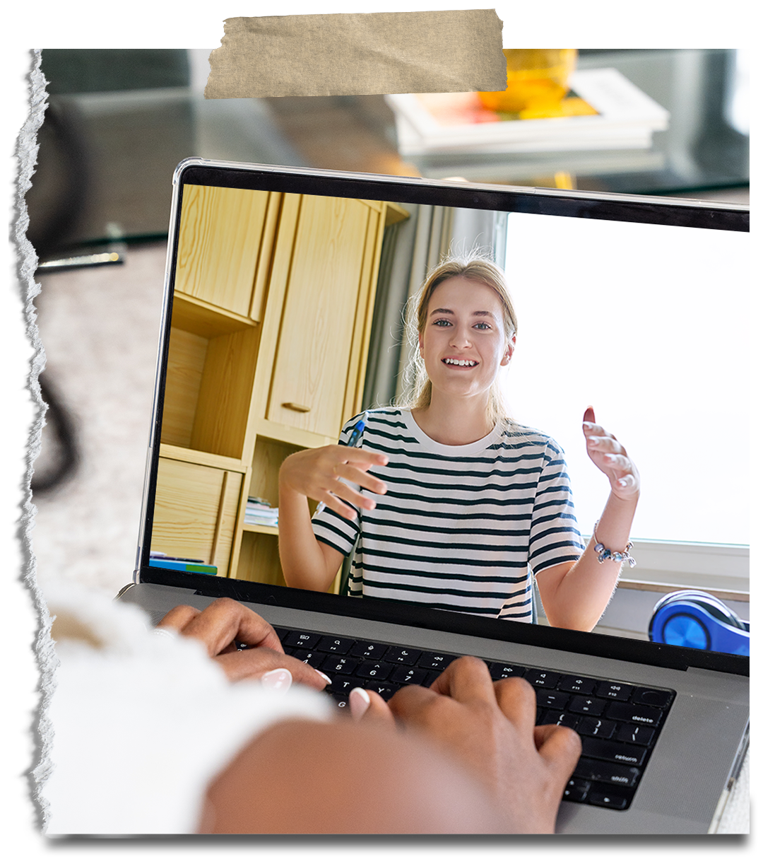 A person taking a photo or video of a woman smiling and gesturing during a video call on a laptop, with the woman's image being displayed on the screen.