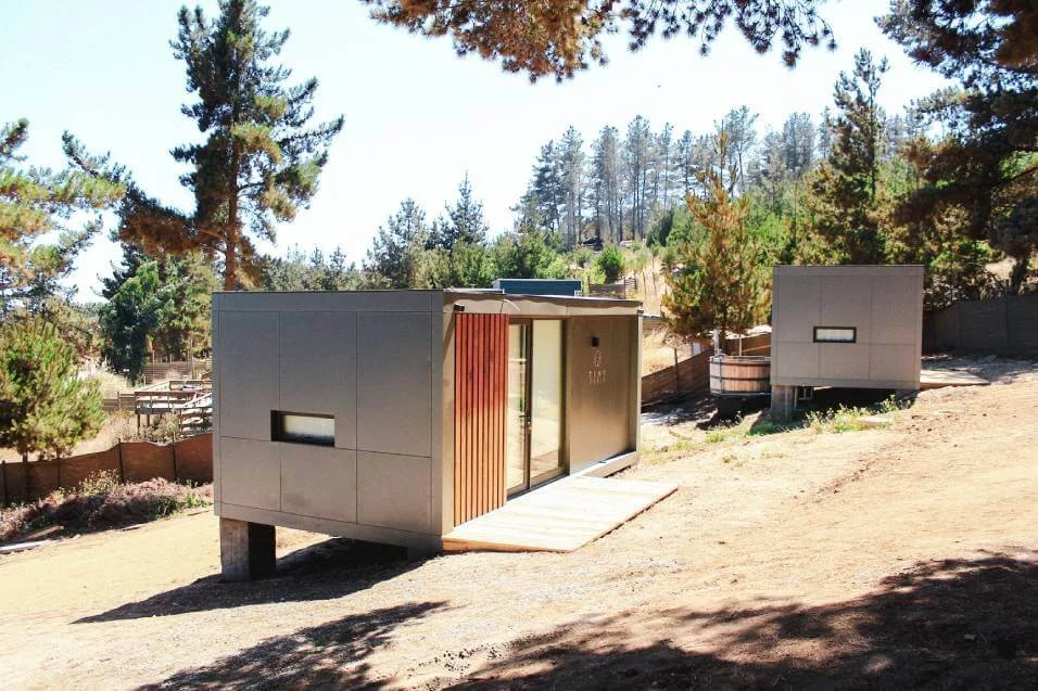 Casas pequeñas modernas en un entorno de naturaleza con árboles y colinas.