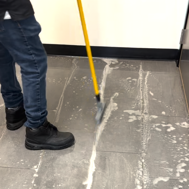 Person cleaning the floor with a mop that has cleaning solution.