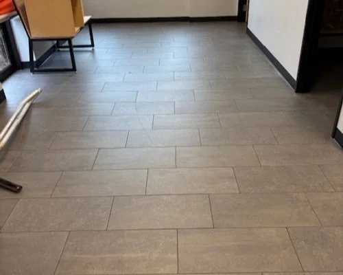 Empty room with wood-look flooring, a small wooden chair, and a window with blinds.