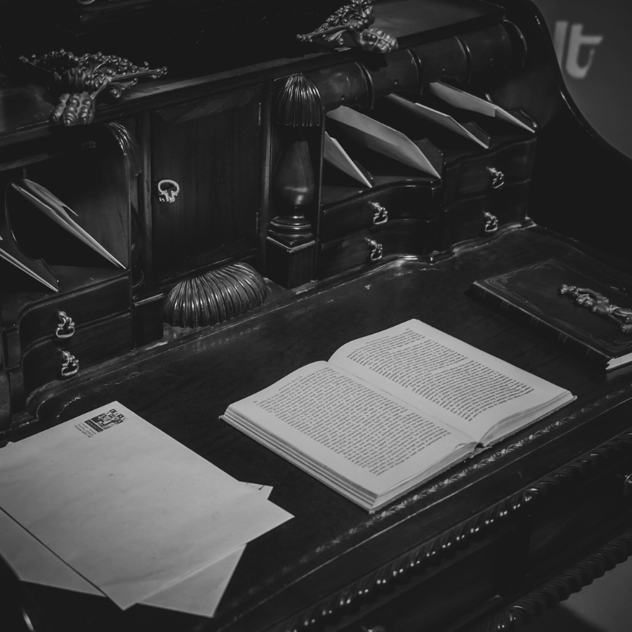 A book lies open on an old wooden work desk
