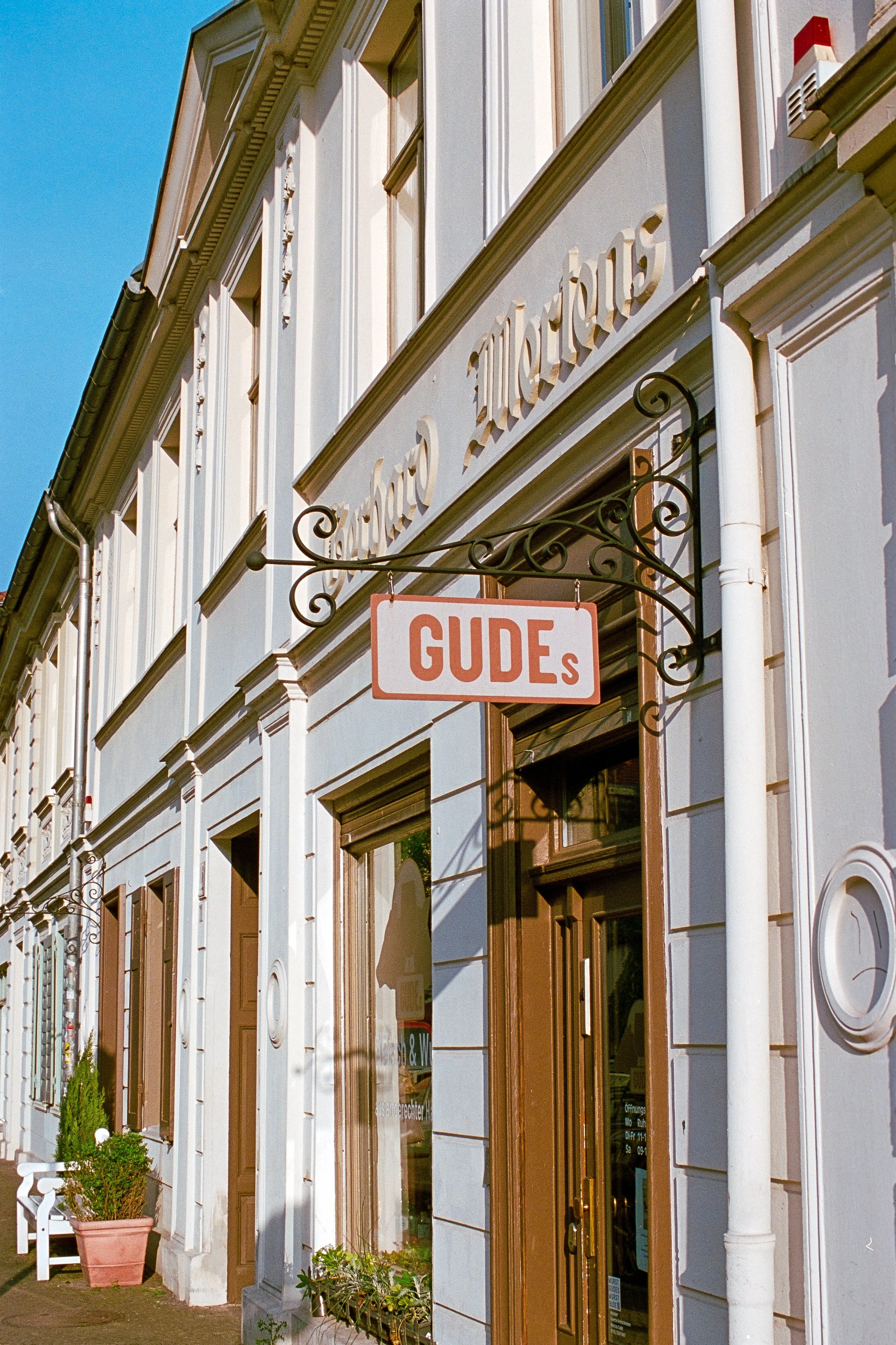 Historisches Gebäude mit weißen Fassaden und Holztüren, ein hängendes Schild mit der Aufschrift 'GUIDE' neben einem Schriftzug 'Salemstolz Marien'.