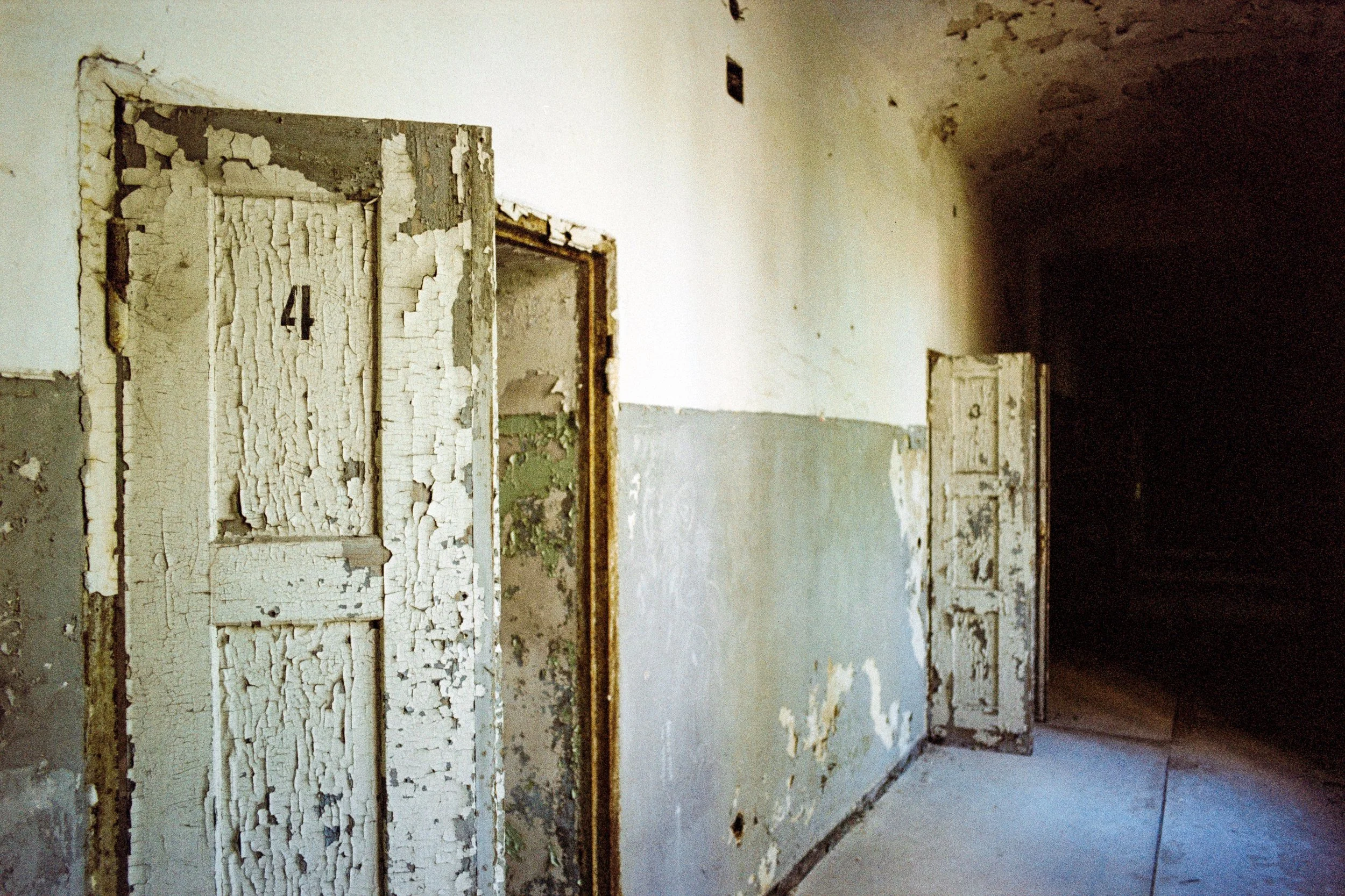 Vergessene, alte Türen in einem verlassenen und verfallenen Gebäude mit peelingnder Farbe und bröckelnder Wand