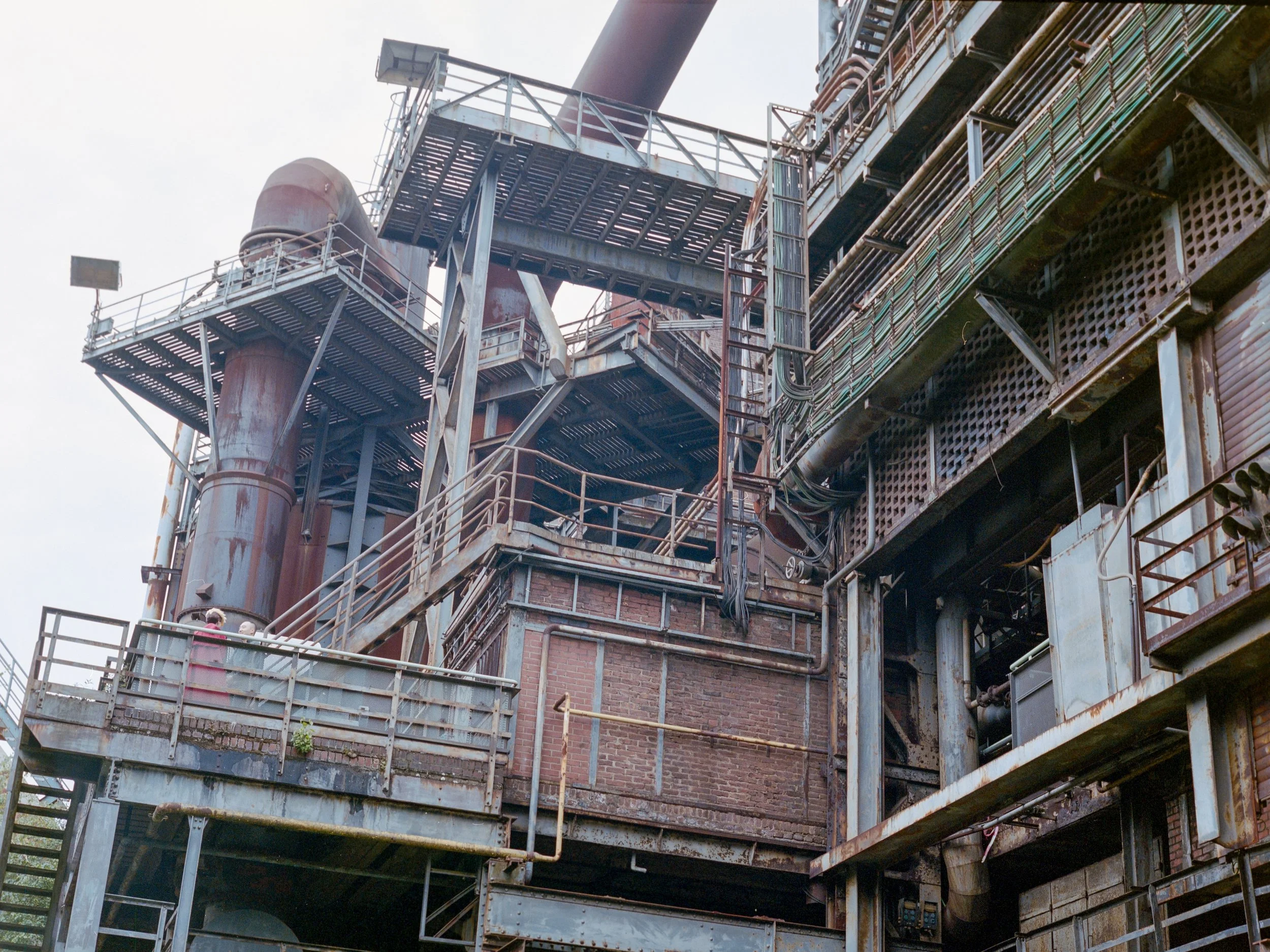 Ein verrosteter Industriekomplex mit Metalltreppen, Rohren und Balkonen aus Metall und Ziegeln.