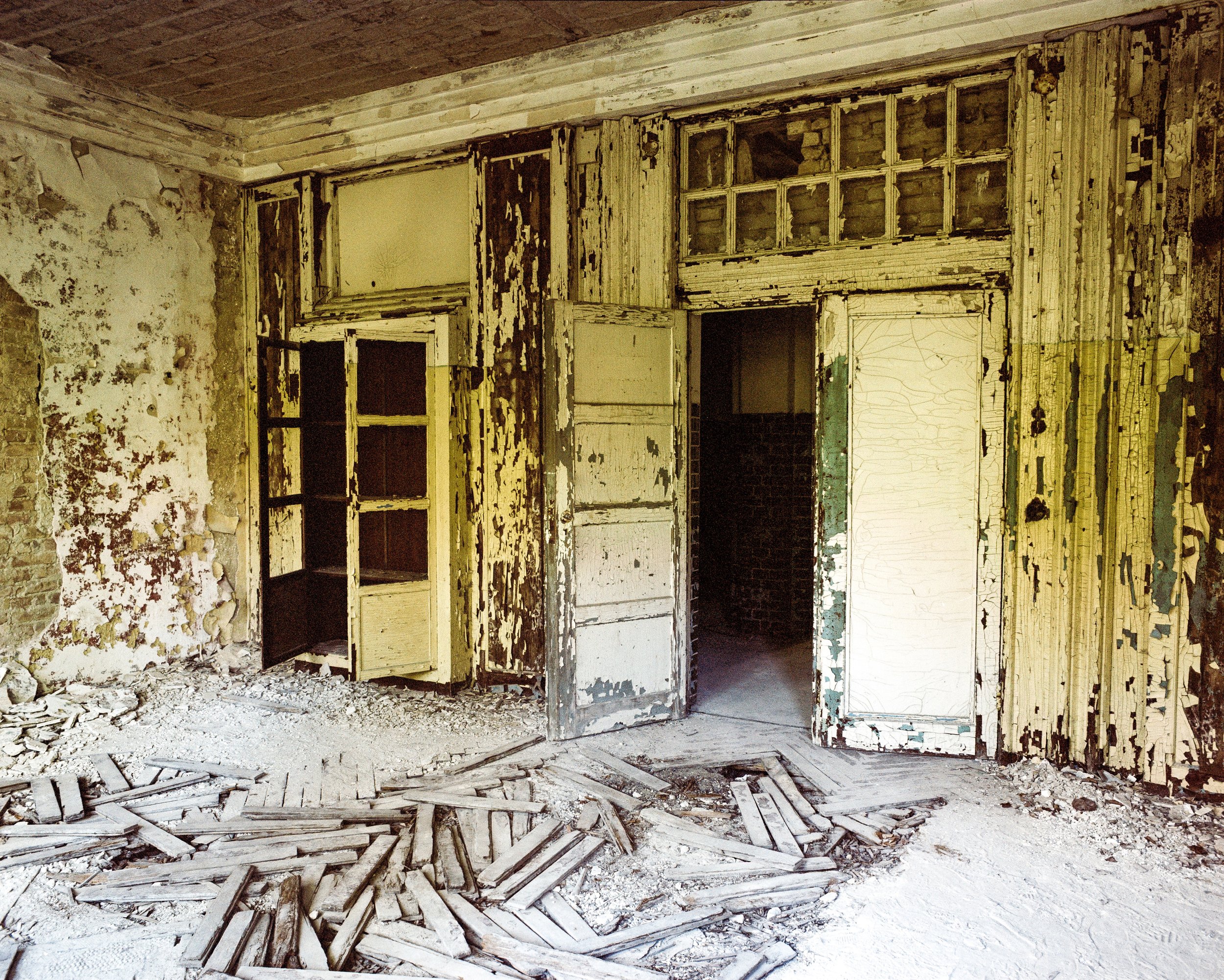 Verfallenes, altes Haus mit beschädigten Wänden und Türen, Dielen auf dem Boden in einem ruinösen Zustand.