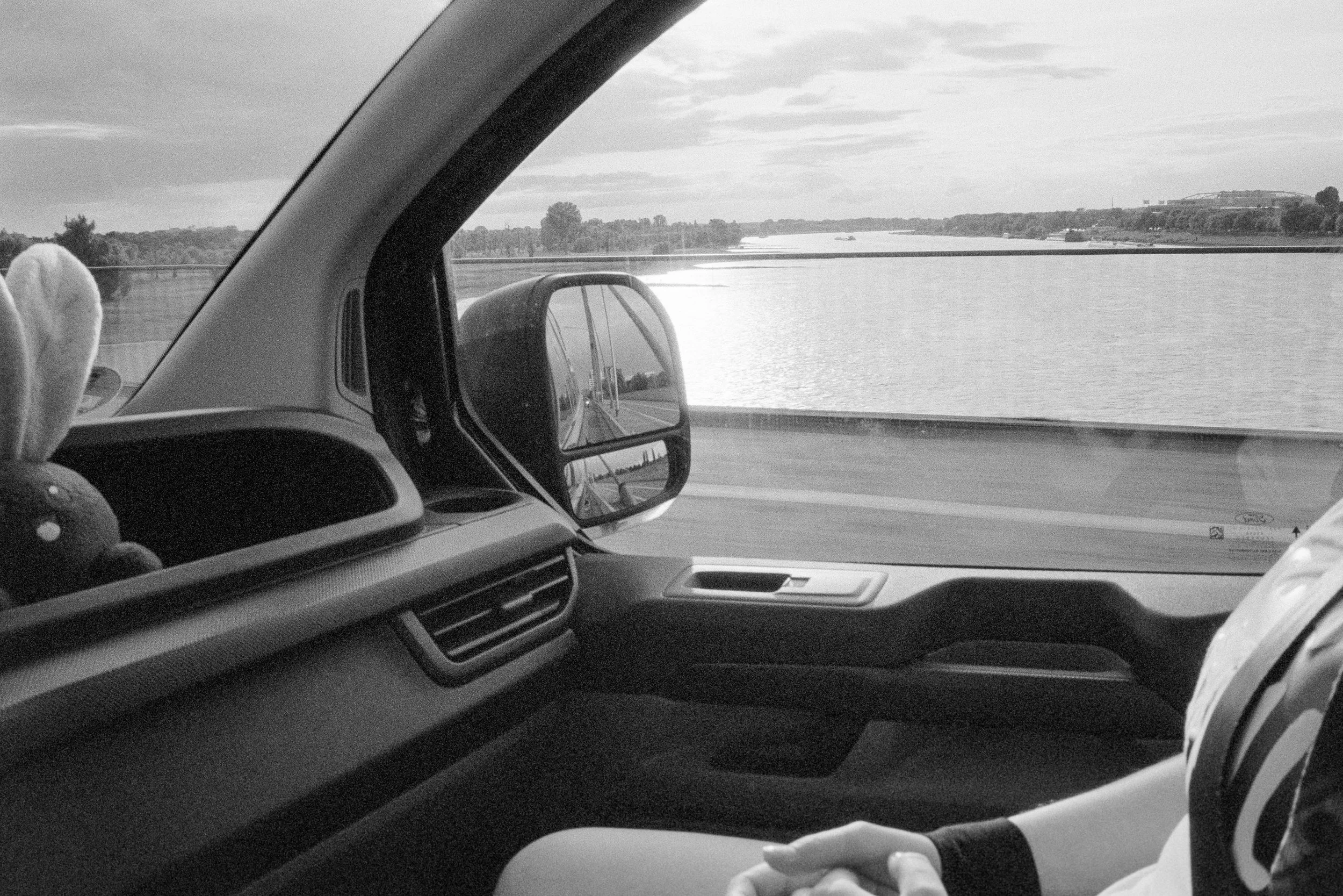 Blick aus dem Fahrzeuginneren auf ein gekacheltes Wasser und den Himmel, während die Person im Beifahrersitz sitzt.