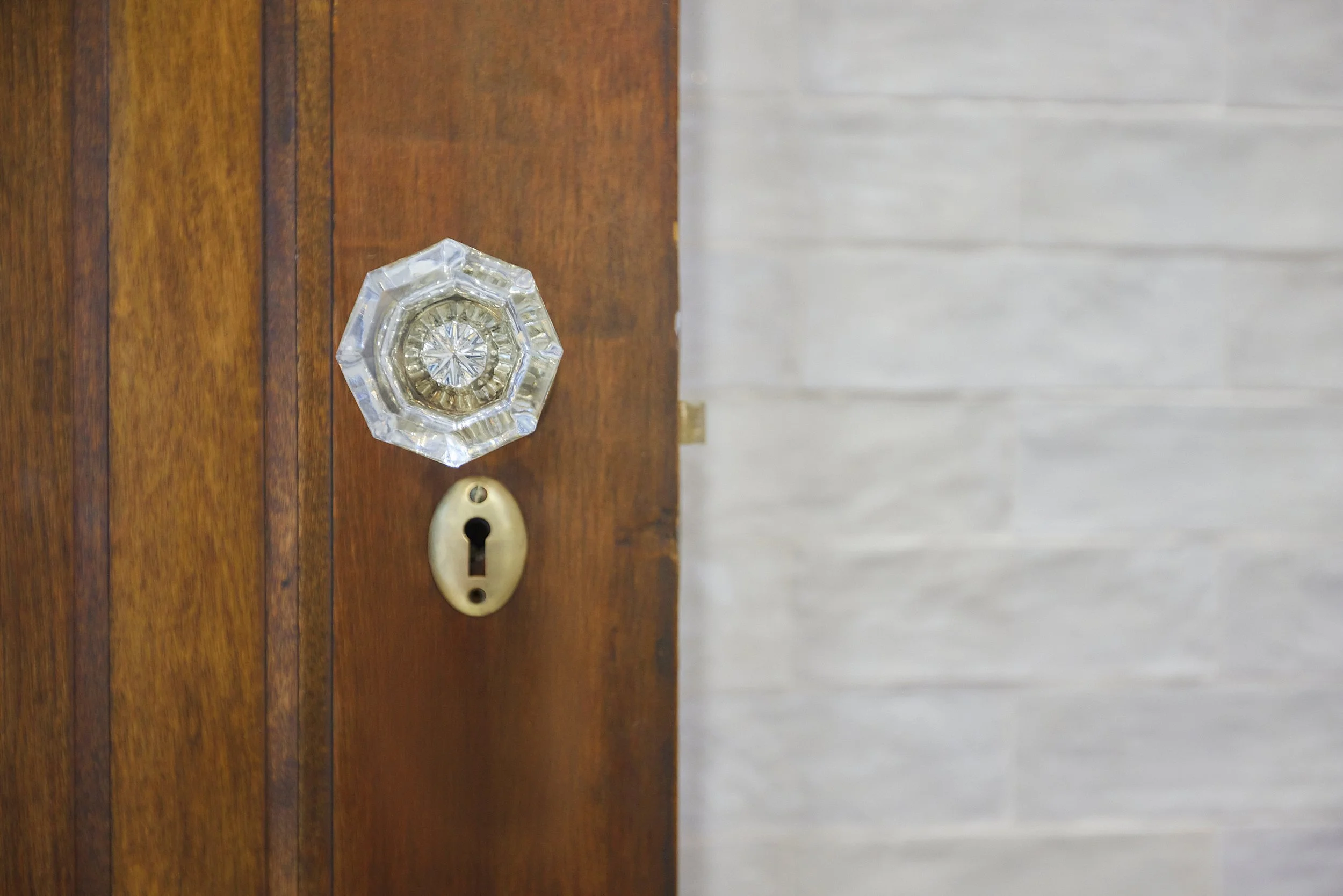 Close-up of a wooden door with a vintage glass doorknob and an old-fashioned keyhole.
