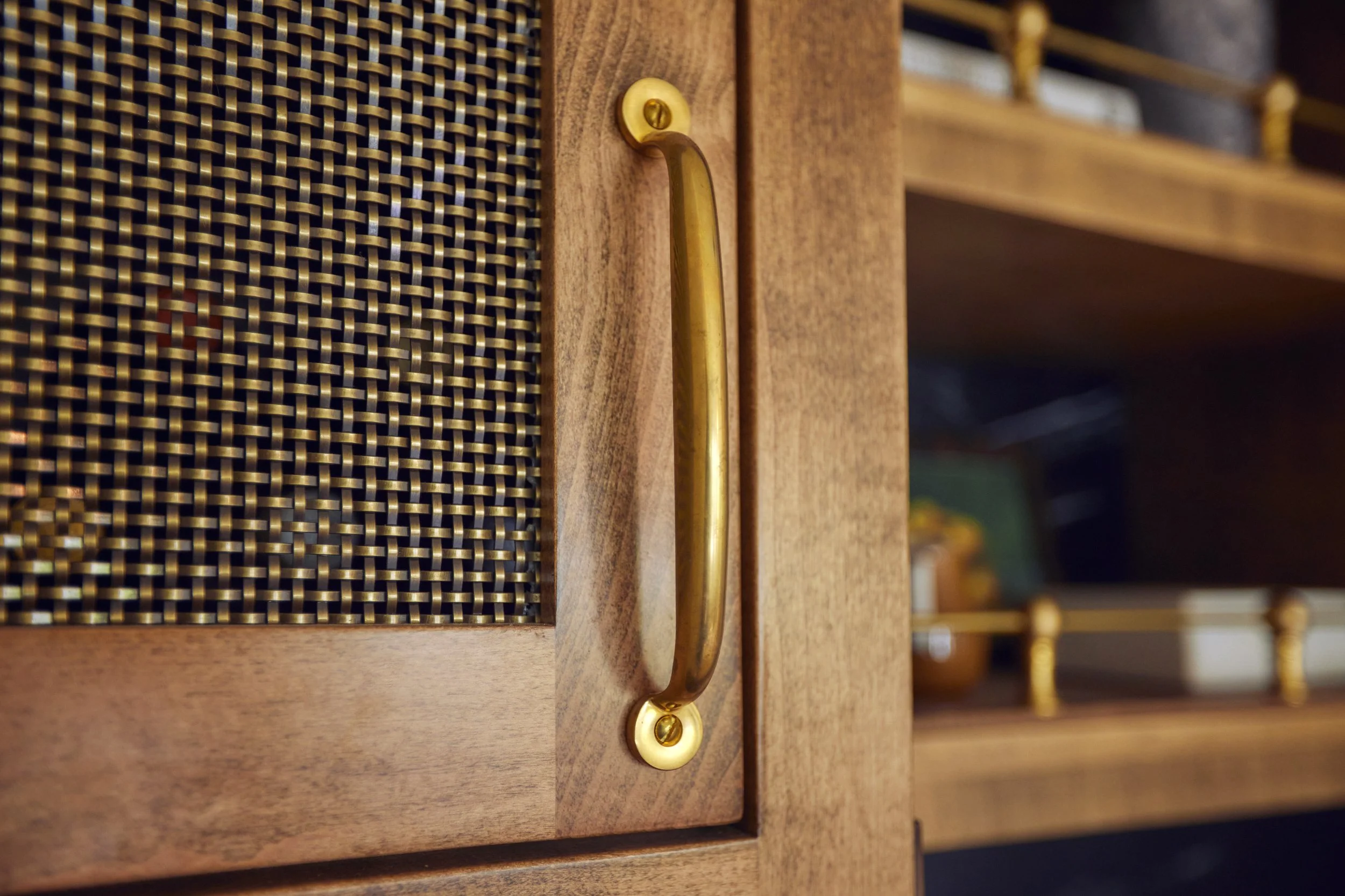 Close-up of a wooden cabinet door with a brass handle and a woven rattan panel.