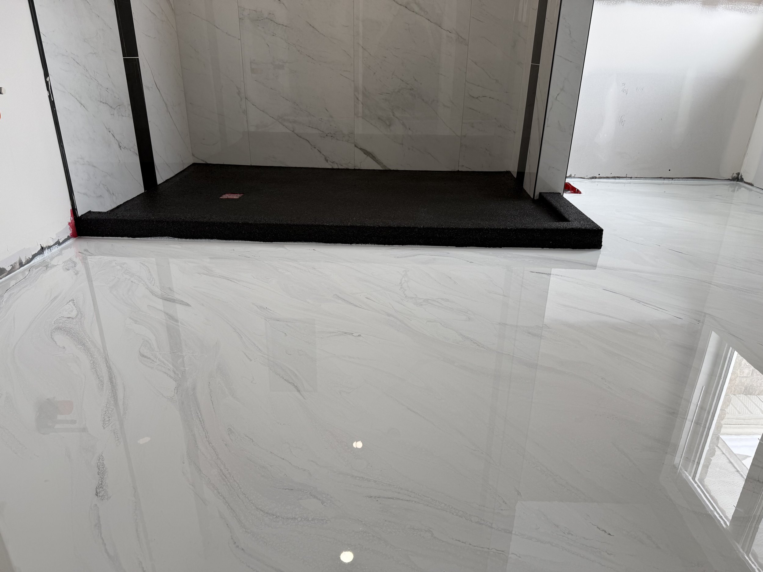 Marble flooring with a glossy finish and gray veining, leading to an elevator with dark flooring and marble walls.