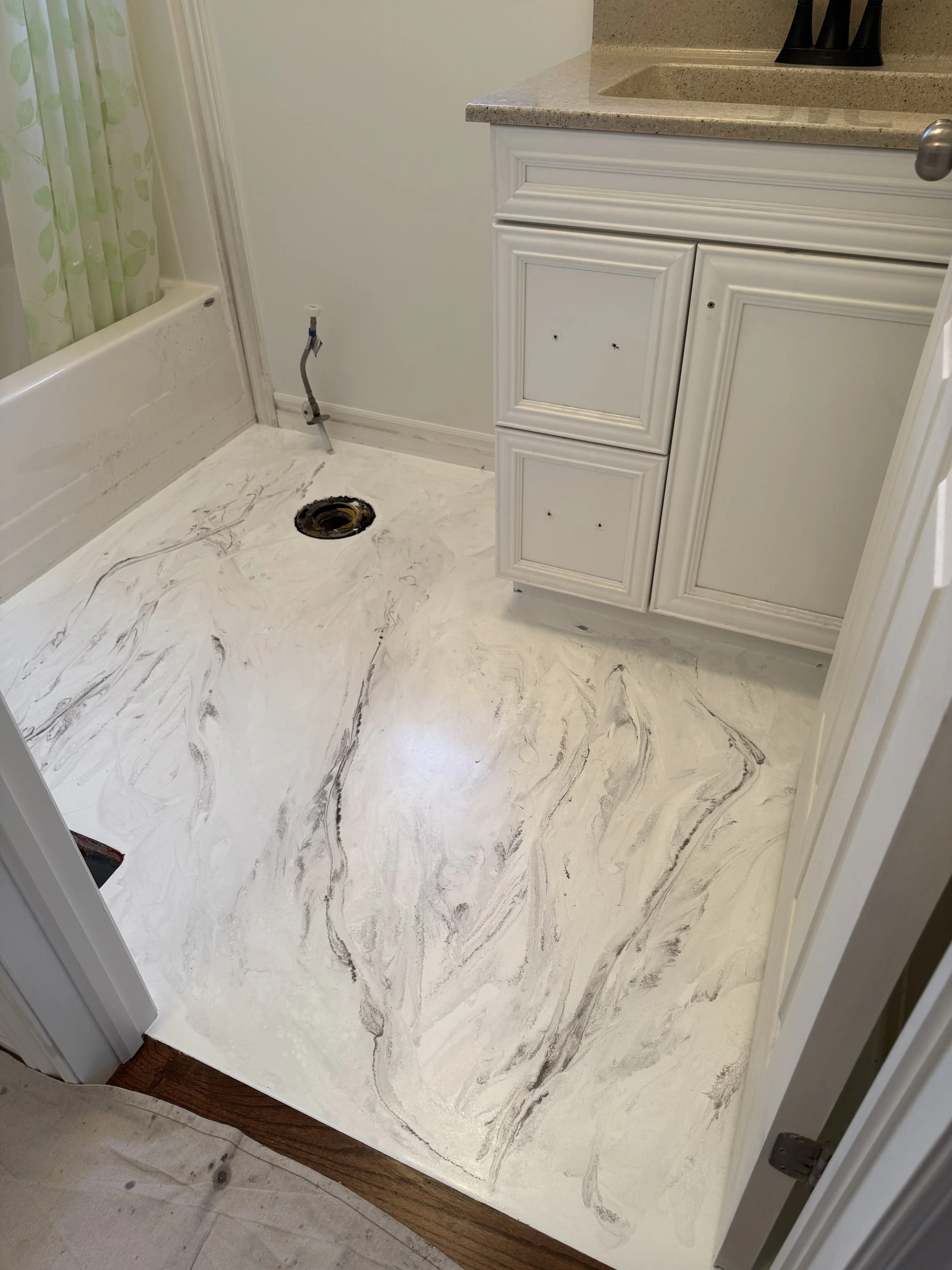 Bathroom with marble-style vinyl epoxy flooring, white cabinetry, and an empty space with plumbing for a washing machine.