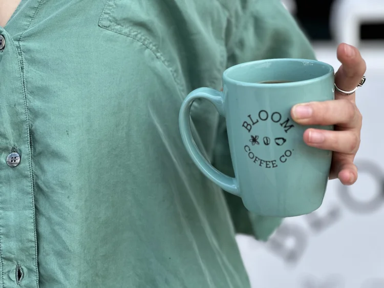 A guest holding a mint-green Bloom Coffee Co. cup