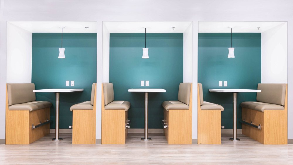 Three booth study tables with teal walls and pendant lights in the CBI Lounge