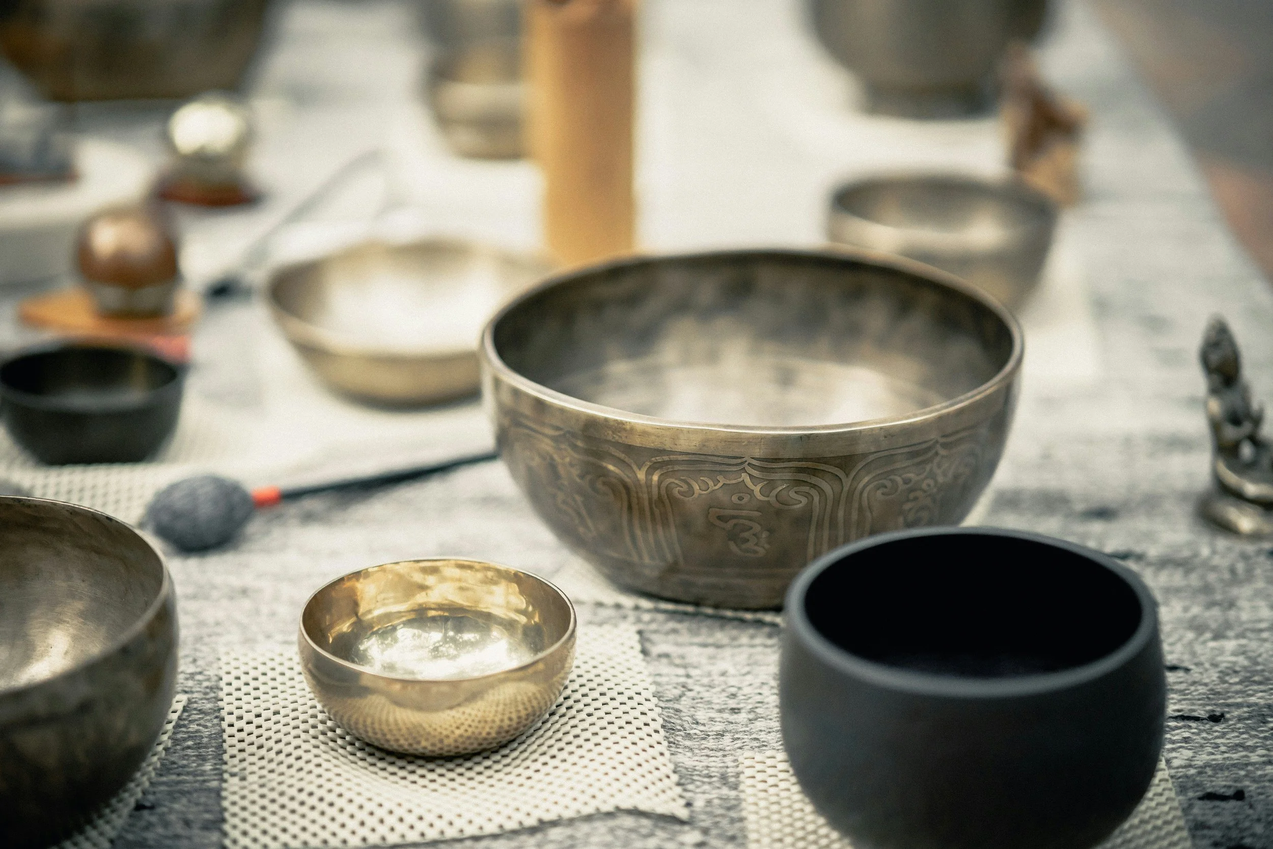 Various singing bowls and spiritual artifacts arranged on a table, likely for meditation or spiritual practice.