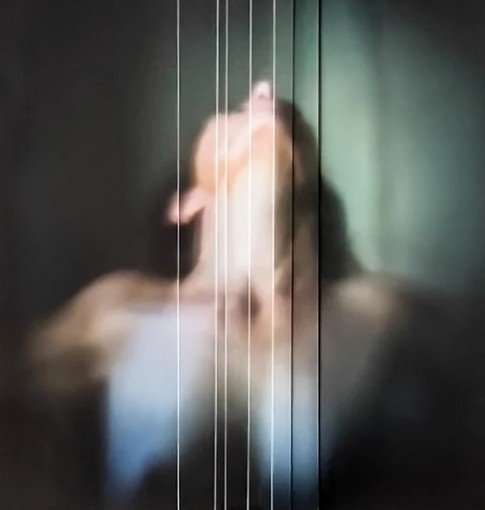 A mirror with vertical lines reflecting a woman applying makeup or adjusting her hair.