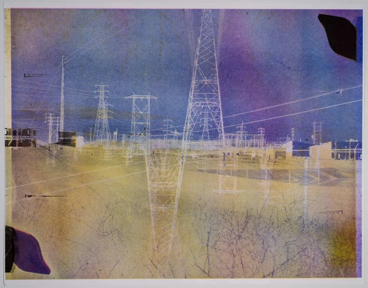 Image of electrical power lines and pylons in a landscape with a blue sky.