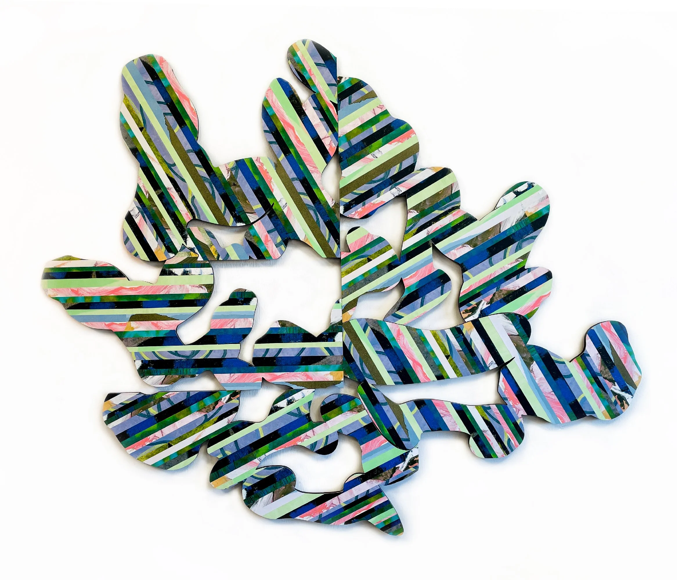 Colorful, striped paper cutout of a leaf made from layered, patterned strips of paper against a white background.