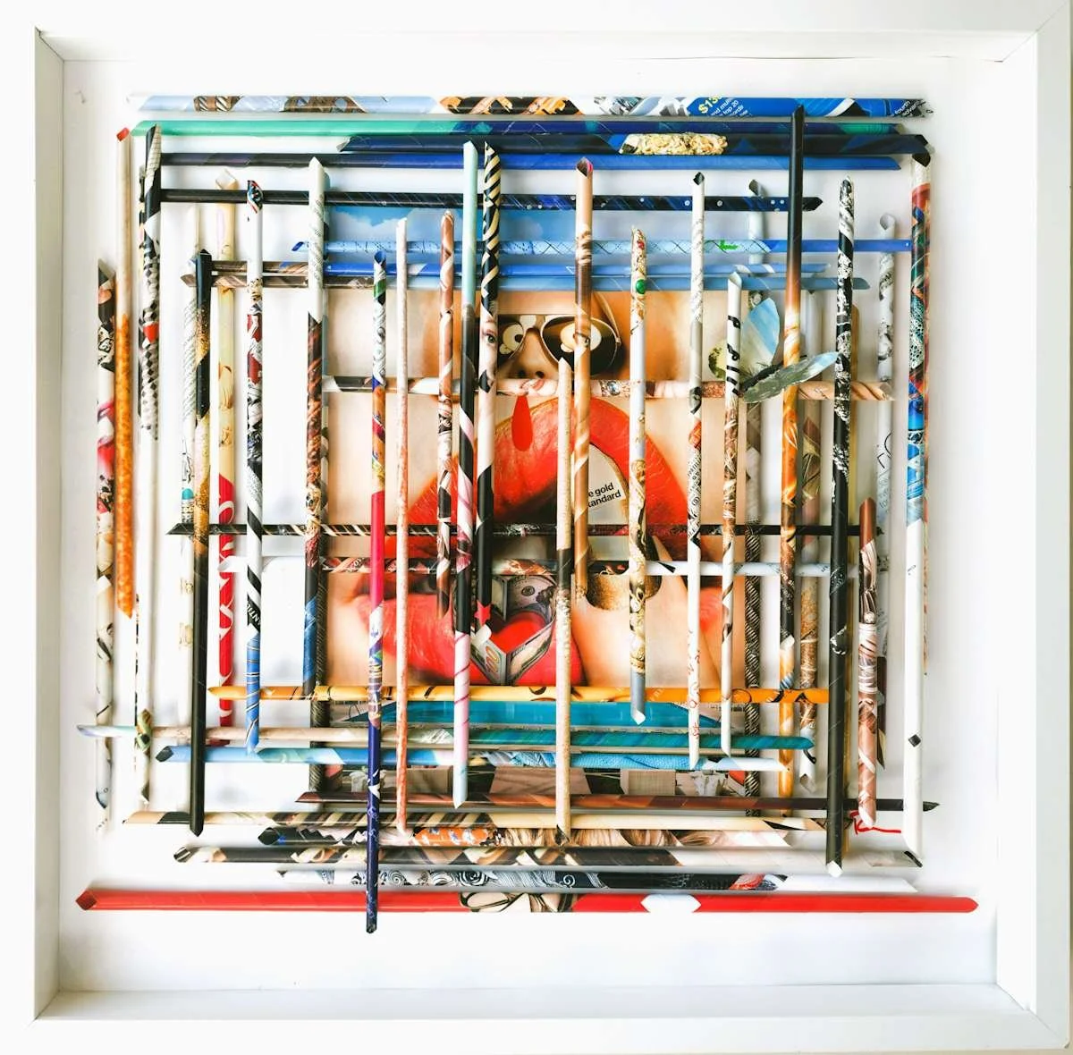 Mixed media art piece made of colorful painted and collaged chopsticks arranged in a grid with a portrait of a woman with sunglasses and lipstick in the background.