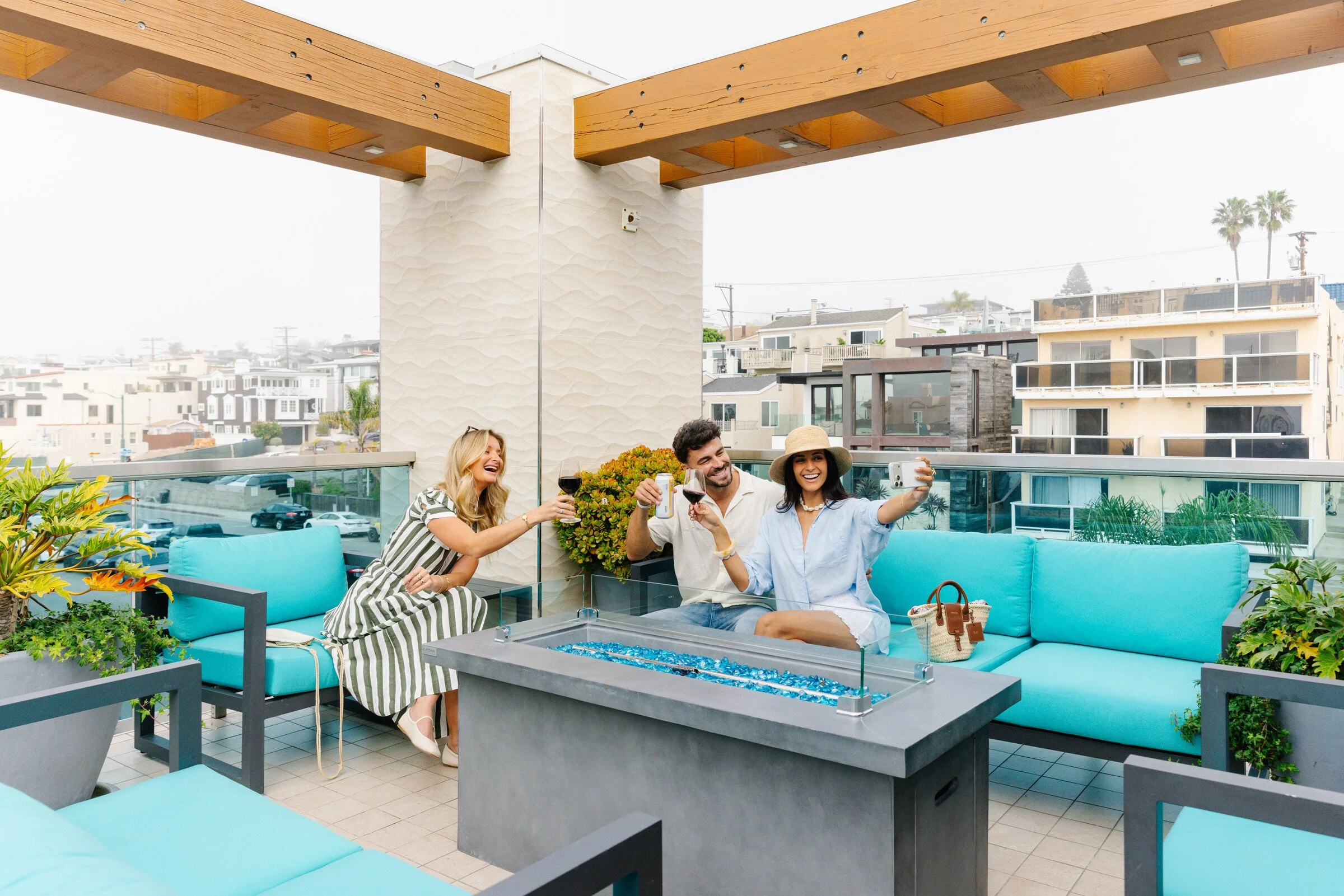 Guests gathered around a fire pit beneath the pergola at H2O Hermosa Beach Hotel’s rooftop lounge
